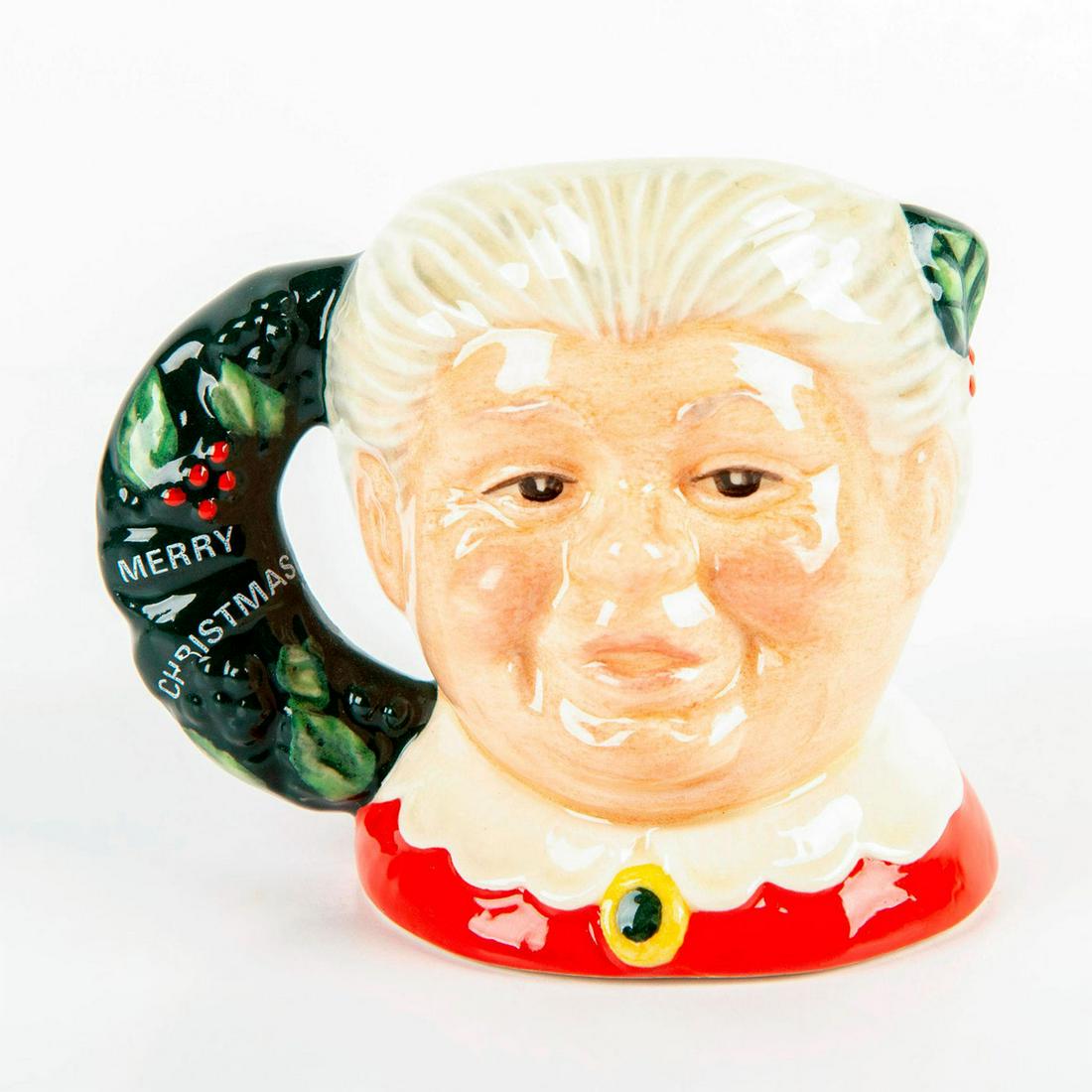 Mrs. Claus D6922 - Mini - Royal Doulton Character Jug: Style One, Christmas wreath handle. Red, cream, and green coloration. Artist: Stanley J. Taylor Issued: 1992 Dimensions: 2.5"H Manufacturer: Royal Doulton Country of Origin: England