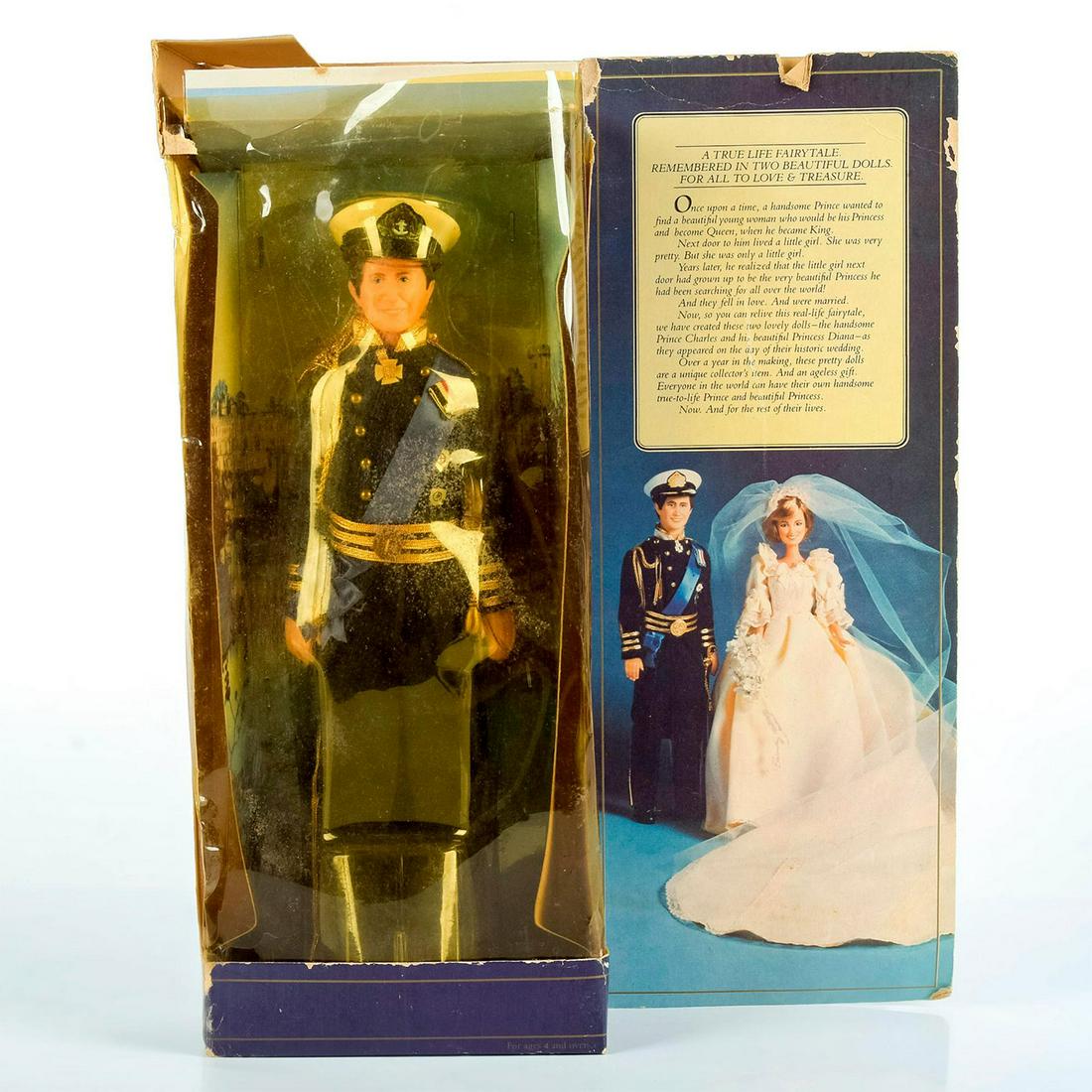 Goldberger Doll, Charles, Prince Of Wales 5002: Wears a Royal Navy commander's full dress uniform, decorated with medals and gold tassels. Includes original box and doll stand. Major wear to box. Doll in good condition. Doll: 12"H. Box: 15"H. 11.5"