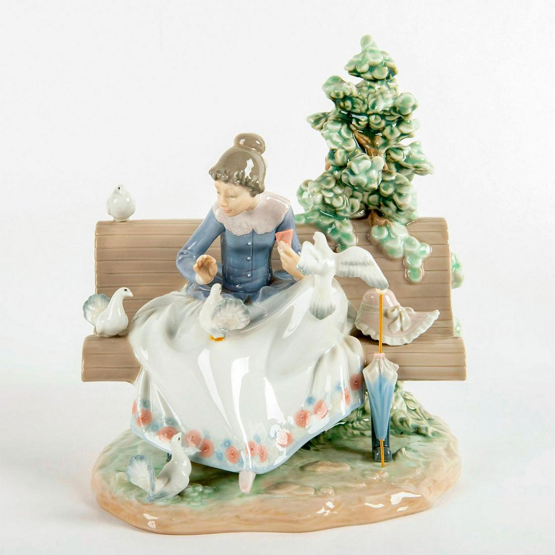 Feeding the Pigeons 1005428 - Lladro Porcelain Figurine: Glossy finish; Woman sitting on a park bench, feeding pigeons. Lladro backstamp. Original box included. Artist: Regino Torrijos Dimensions: 9"H Issued: 1987 - 1989 Manufacturer: Lladro Country of Orig