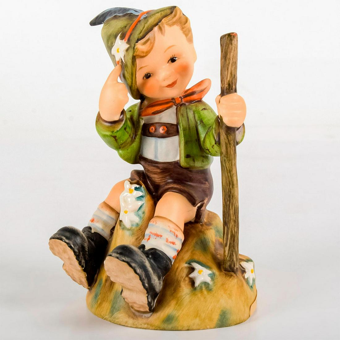 Mountaineer 315 - Goebel Hummel Figurine: Matte porcelain, hand painted. Wears a green hat adorned with a feather and blossom; holds a walking stick. 'M. I. Hummel' inscribed on base. Goebel backstamp. Age related crazing. Weight: 6.7