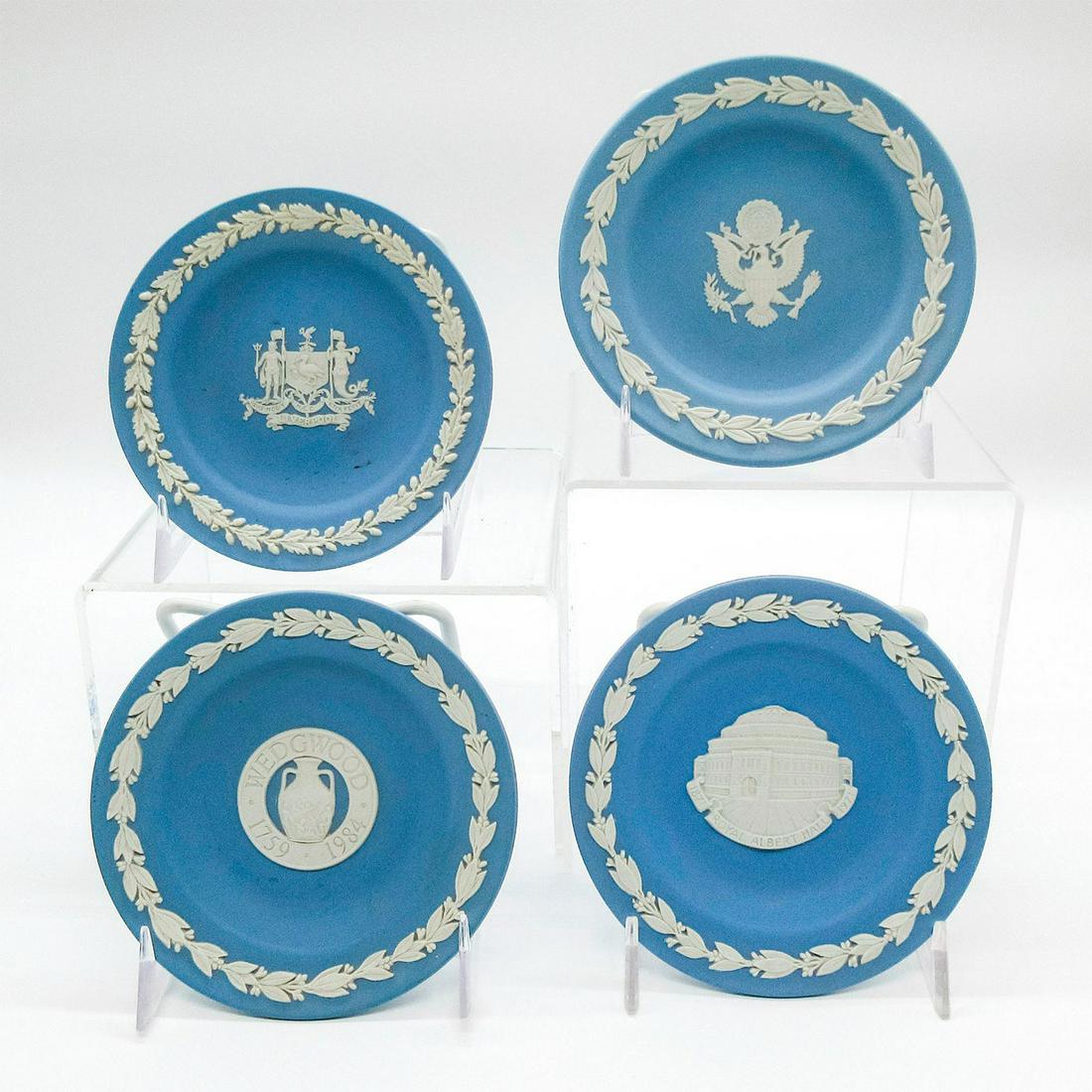 Set of 4 Small Wedgwood Jasperware Plates: Four matte blue with white jasperware plates displaying coat of arms and Royal Albert Hall with floral rim details. Wedgwood made in England impressed on the back. Minor fractures to white decorations