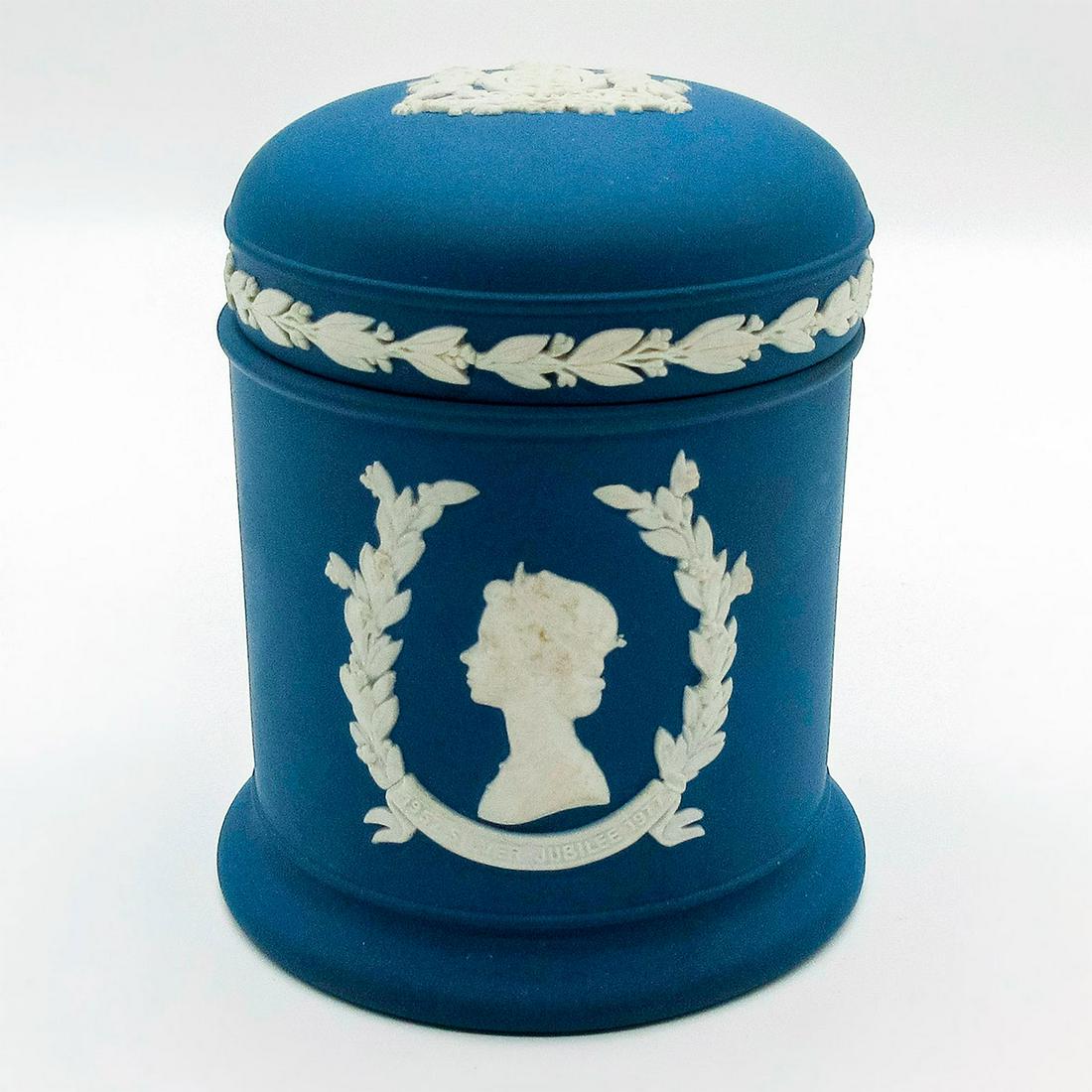 Wedgwood Royal Blue Jasperware, Lidded Jar: Silver Jubilee Queen and Duke matte royal blue lidded round jar with white sprigged decorations in relief. Wedgwood impressed on the bottom. Minor age related hairline cracks in white sprigs. Weight: 