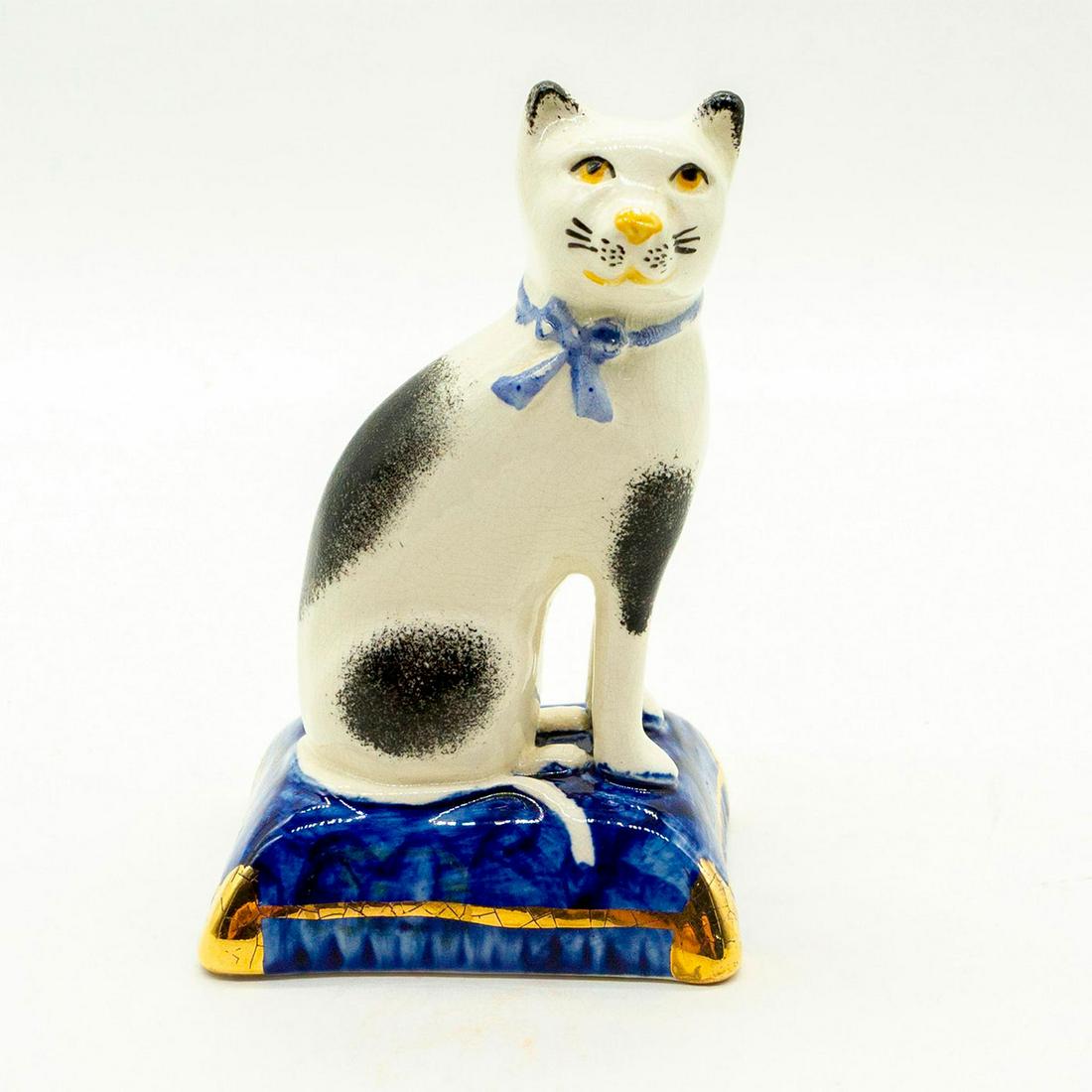 Antique Staffordshire Creamware Figurine, Royal Cat: White and black cat with blue ribbon, sitting on a royal blue pillow with gilt accents. Minor crazing throughout. #staffordshire #creamware #earthenware #cat #antique Issued: 20th c. Dimensions: 4"H M