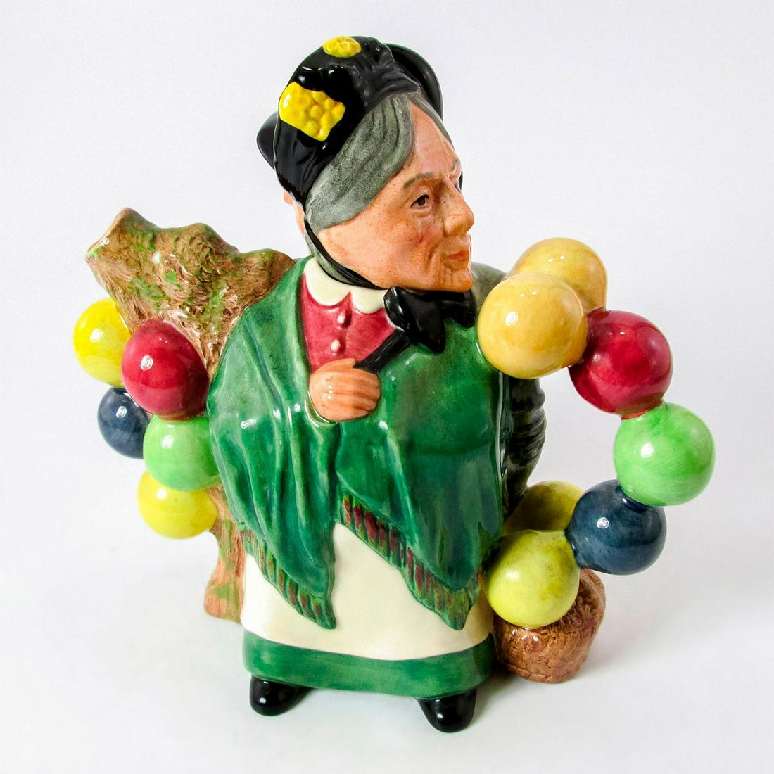 Royal Doulton Character Teapot, Balloon Man And Woman: Woman in green shawl and skirt with white apron on one side and man in brown jacket, rose waistcoat and beige trousers. Multicolored balloons. International Collectors Club Series. Royal Doulton backs