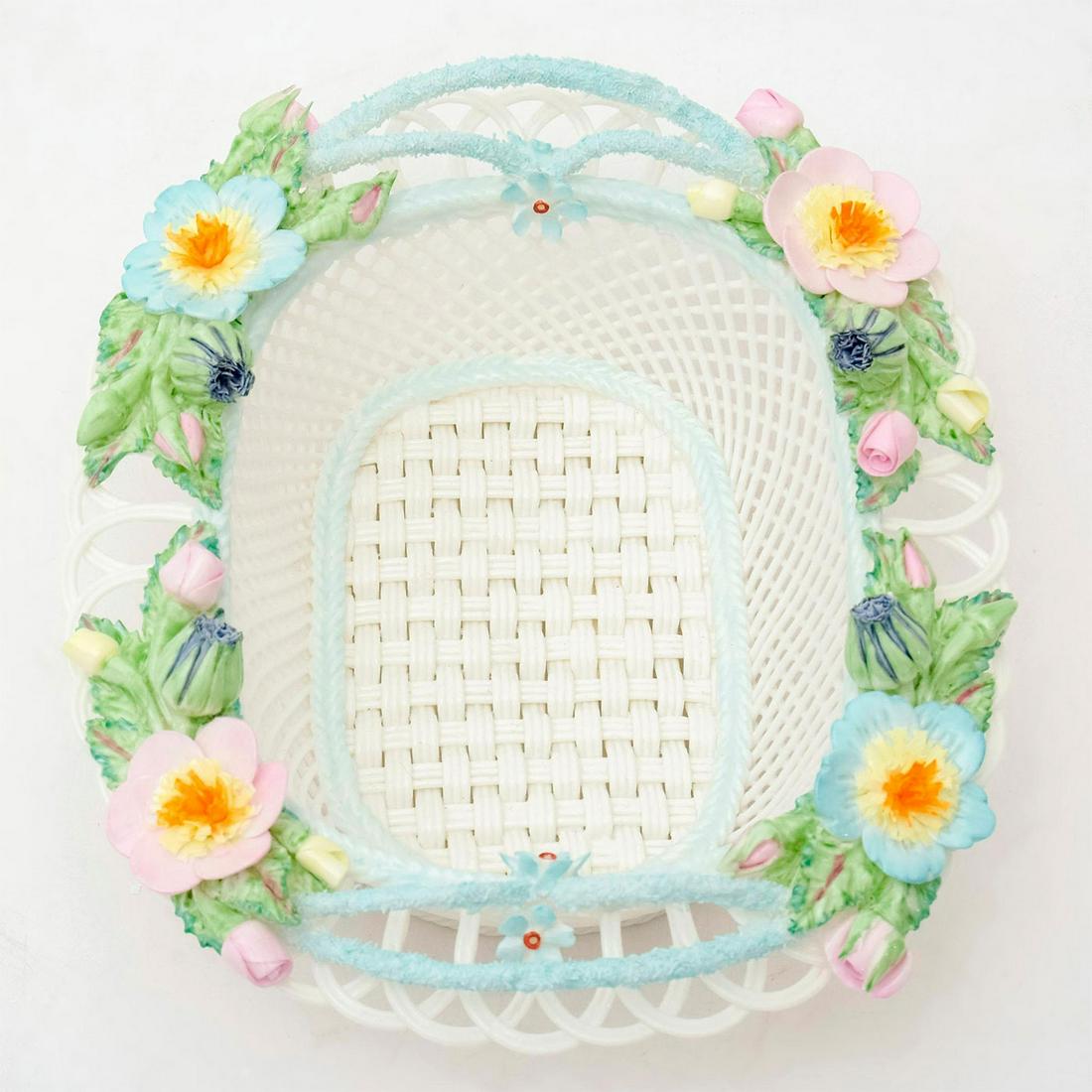 Celtic Weave Irish Parian Woven Basket: Belleek style bone china woven basket with blue borders and colorful flowers adorn the top. 'Celtic Weave' on the bottom. #celticweave Issued: 20th c. Dimensions: 7"L x 6.25"W x 2.5"H Manufacturer: Ce