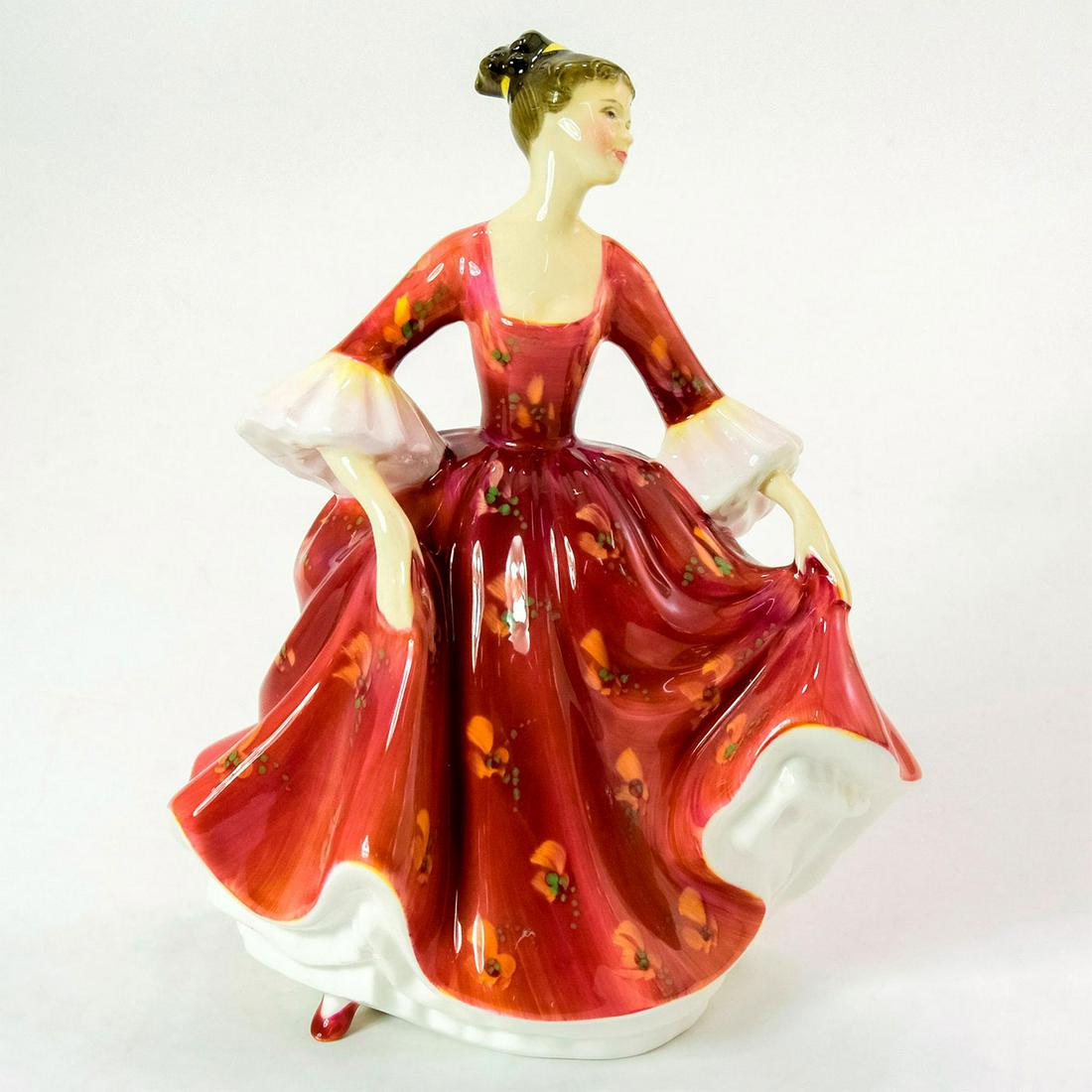 Stephanie HN2811 - Royal Doulton Figurine: Bone China. Stephanie wears a red dress with hand painted floral pattern and white sleeves. Series: Peggy Davies Classic. Royal Doulton backstamp. Artist: Peggy Davies Issued: 1983 - 1994 Dimensions: 