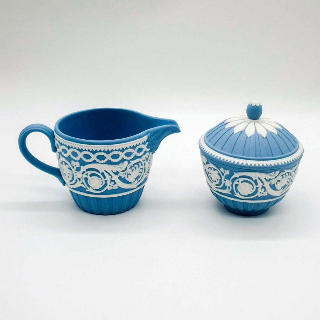 Wedgwood Pale Blue Jasperware Creamer and Lidded Sugar: 250th anniversary edition; white floral patterns in relief. Wedgwood impressed backstamps. Wedgwood 250th Anniversary backstamps. Minor fleabite on sugar bowl lid. Creamer: 3"H x 5.75"W. Sugar Bowl: 4