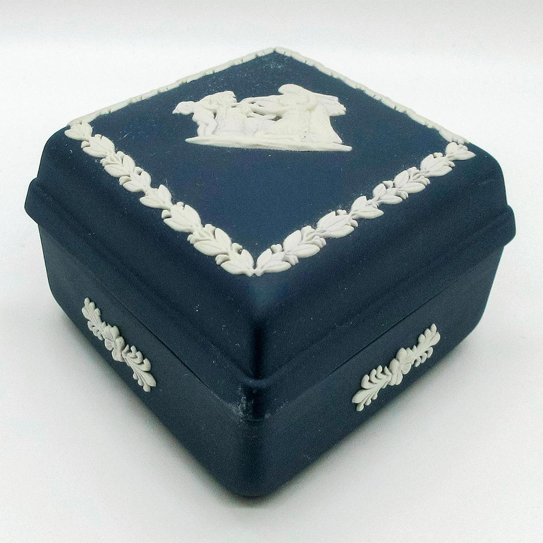 Wedgwood Portland Blue Jasperware Lidded Box: Diamond shaped trinket box; Cupid as Oracle pattern. Matte blue ground; white relief designs; foliate borders. Wedgwood impressed backstamp. #beanbox Issued: 20th c. Dimensions: 5"L Manufacturer: Wedg