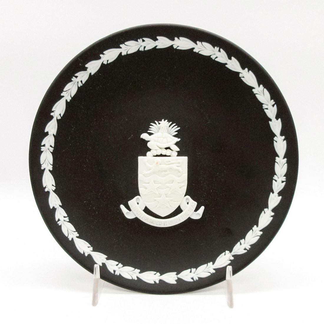 Wedgwood Black Jasperware Plate, Cayman Islands: Matte black ground; white relief design of the coat of arms of the Cayman Islands; foliate border. Wedgwood impressed backstamp. #CaymanIslands Issued: 20th c. Dimensions: 6.5" dia Manufacturer: Wedgw