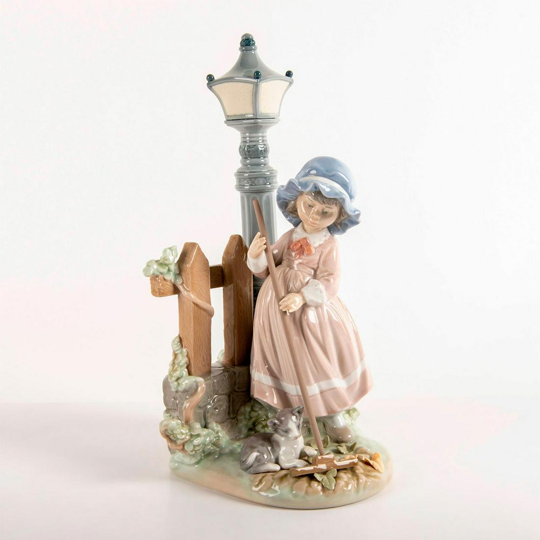 Fall Clean Up 1005286 - Lladro Porcelain Figurine: Glossy finish; Girl sweeping up, next to a cat, fence, and lamppost. Lladro backstamp. Does not included original box. Artist: Antonio Ramos Issued: 1985 - 2007 Dimensions: 13"H x 6.5"W Manufacturer: 