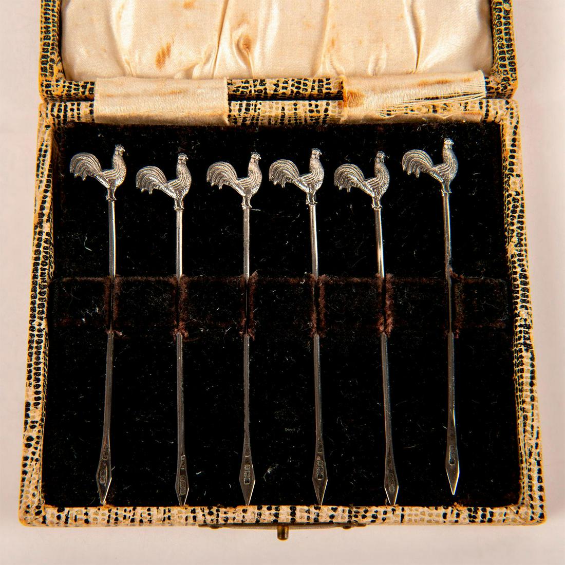 Cased Set of Sterling Silver Cockerel Cocktail Sticks: A vintage cased set of six solid silver cocktail sticks, with embossed cockerel terminals. Each cocktail stick is engraved with Adolph Scott's initials. The case holds all 6 cocktail sticks, with 
