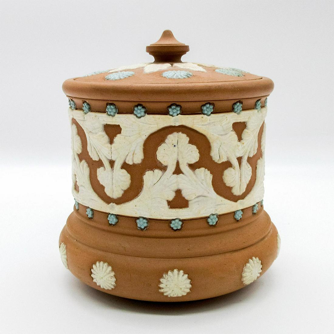 Doulton Lambeth Silicon Ware Tobacco Jar: Matte brown lidded jar with applied blue and white foliate design and applied rosettes encircling body. Doulton Lambeth Silicon backstamp. Age related wear. Weight: 1 lb #tobaccojar #liddedjar Issued: