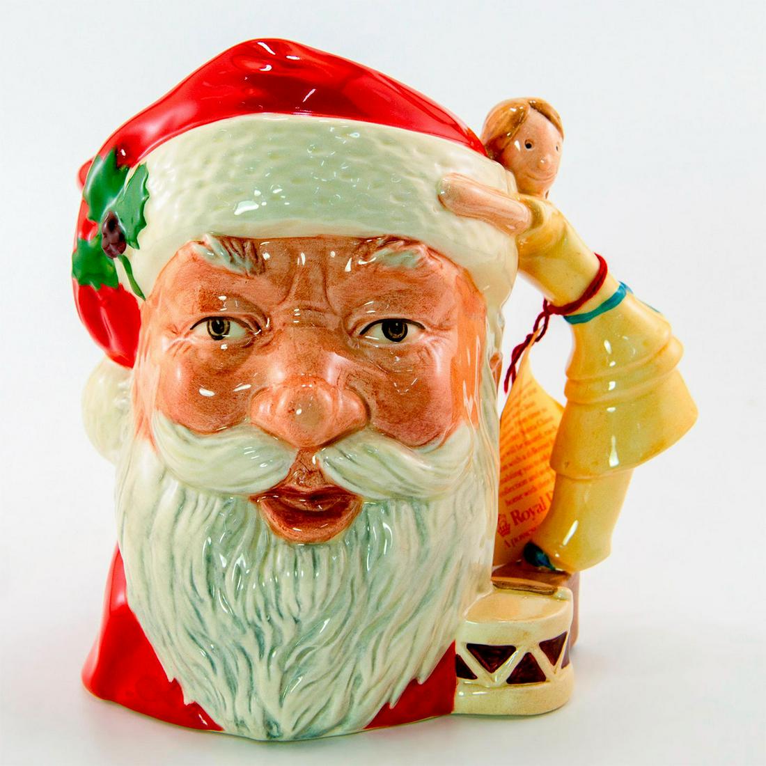 Santa (Doll & Drum) D6668 - Large - Royal Doulton Character Jug: Style One, doll and drum handle. Red, white, and light brown coloration. Royal Doulton backstamp. Original tag tied on the handle. #royaldoulton #characterjug #santaclaus Artist: Michael Abberley Issu