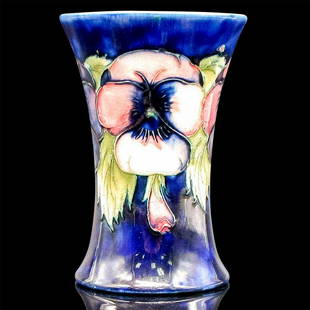 Moorcroft Pottery Trumpet Vase, Pansy: Hand painted in vibrant deep blue ground decorated in colorful hues of pink, plum and white petals with green foliage. Made in England and Potter to HM Queen with W. Moorcroft signature backstamp.