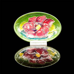 Moorcroft Pottery Trinket Dish, Clematis: Oval ceramic in green with blue base decorated with broad purple flower with yellow pistil and yellow foliage. Moorcroft and Made in England backstamp. #moorcroft #trinket #pottery #clematis 