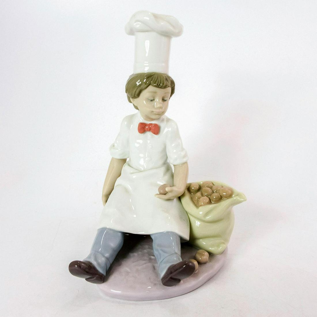 Chef's Apprentice 1006233 - Lladro Porcelain Figurine: Glossy, Lladro backstamp. Artist: Antonio Ramos Issued: 1995-1998 Dimensions: 8"H Manufacturer: Lladro Country of Origin: Spain