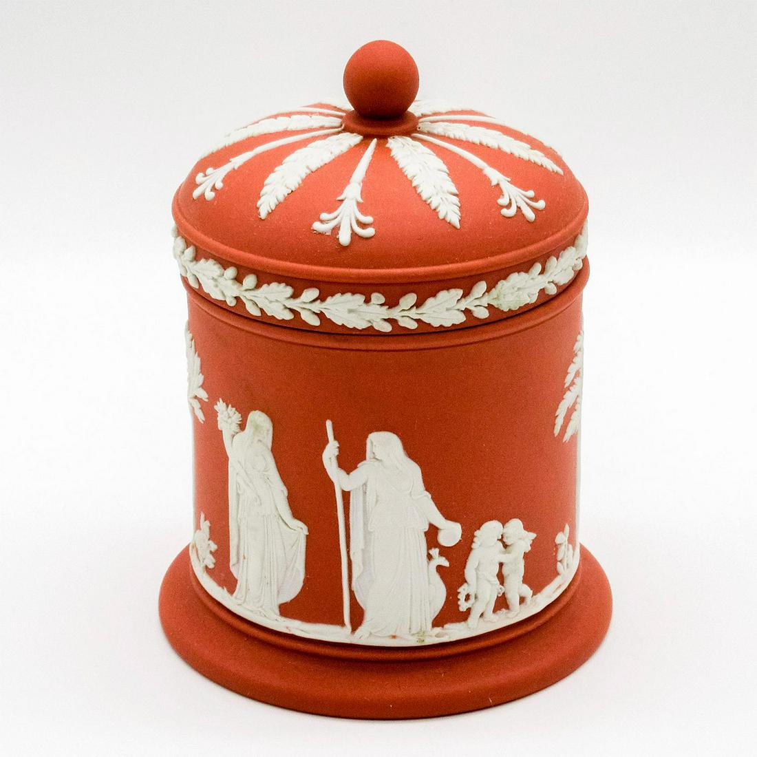 Wedgwood Jasperware Terracotta Lidded Jar: White relief floral patterns and Grecian inspired scenes of cherubs and robed adults. Wedgwood impressed on base. Good condition. #wedgwood #jasperware #terracotta #jar Issued: 20th c. Dimensions: 4.5
