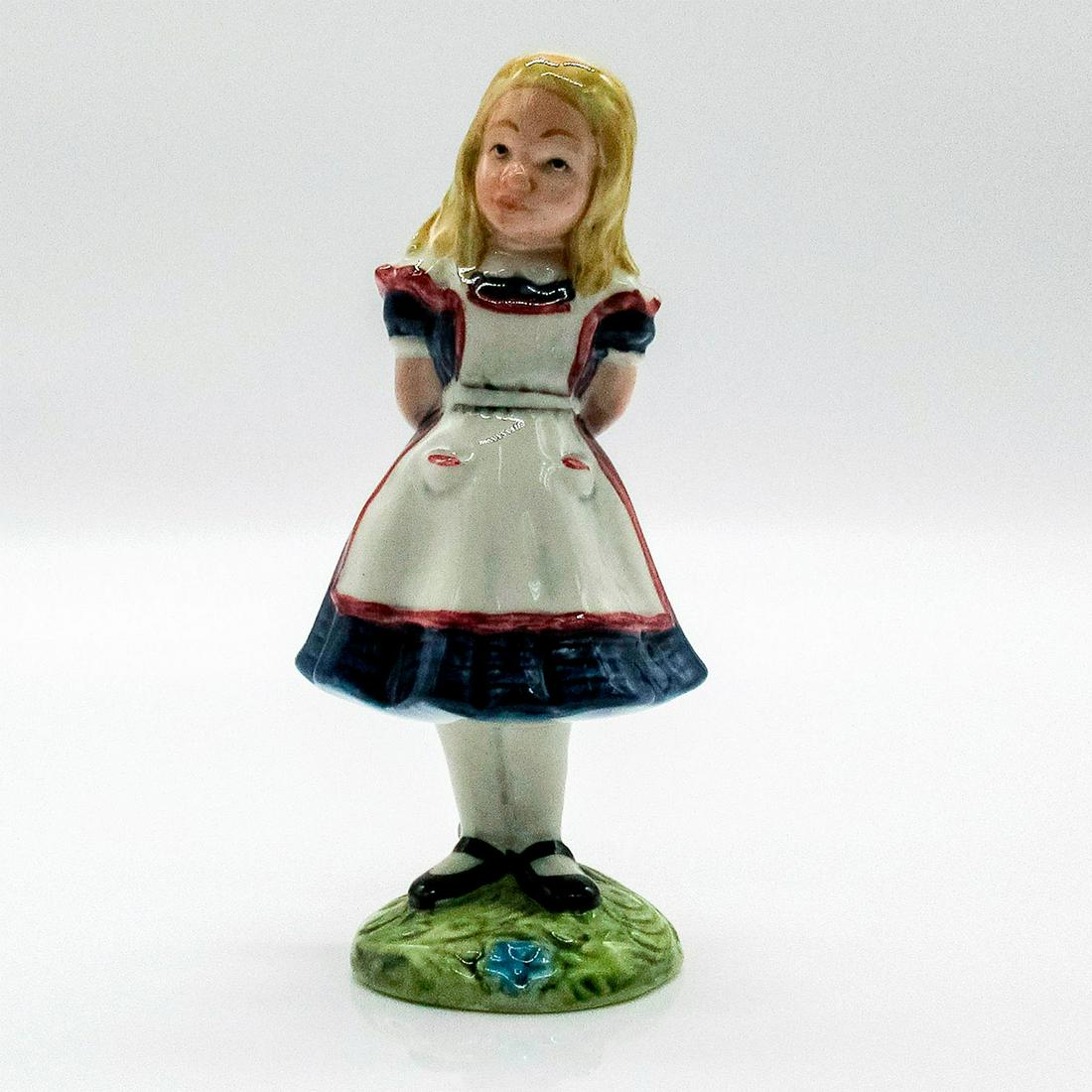 Beswick, Alice Figurine 2476: Hand painted figurine of character Alice from "Alice and Wonderland." Alice is wearing a dark blue dress with a white apron and is standing on a green base with blue flower. Beswick backstamp.