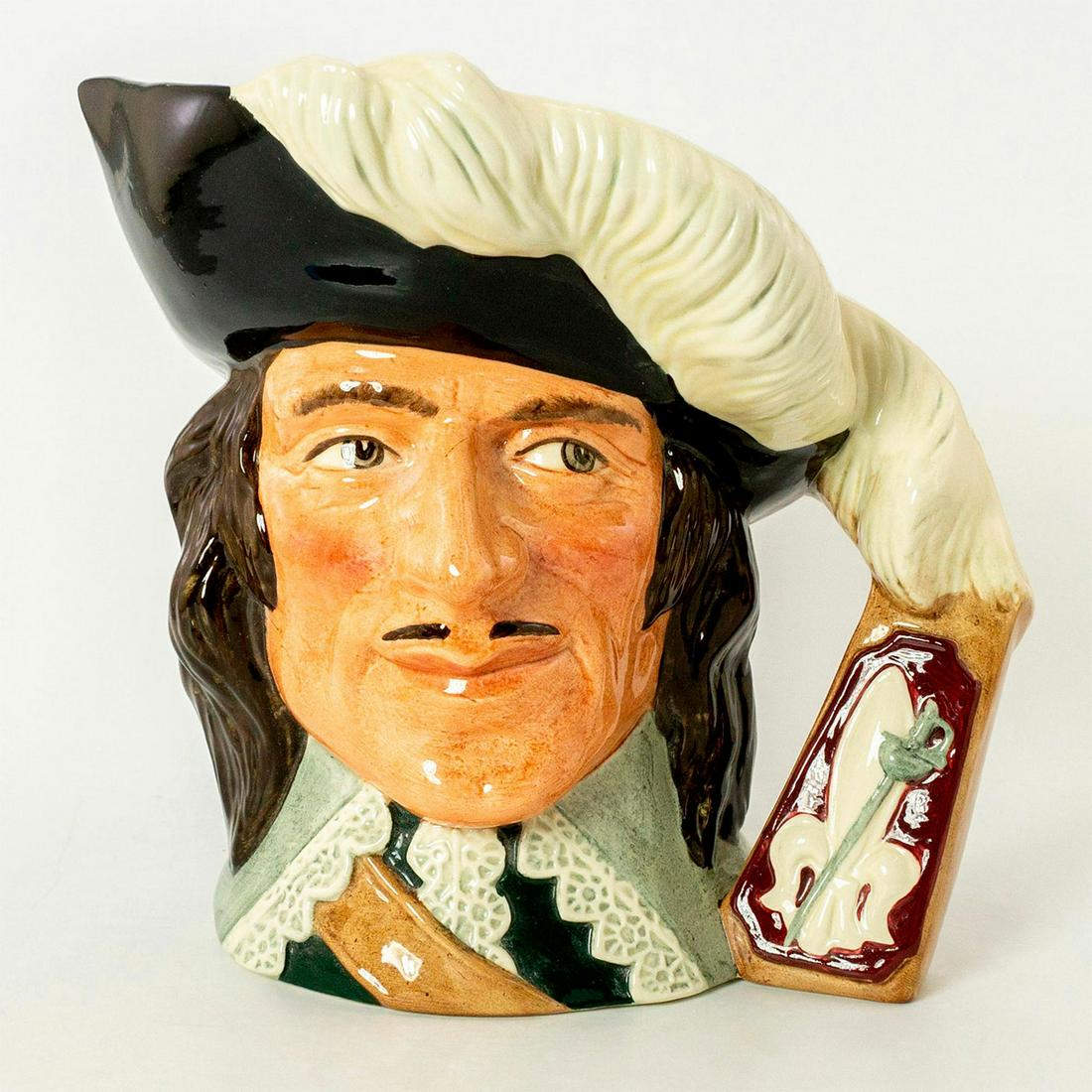 D'Artagnan D6691 - Large - Royal Doulton Character Jug: Extension of the feathers with a fleur-de-lis and sword at base handle. Black hat trimmed with whiter feathers; white lace collar. A character in Alexandre Dumas' lively 19th-century fiction, D'Artagn
