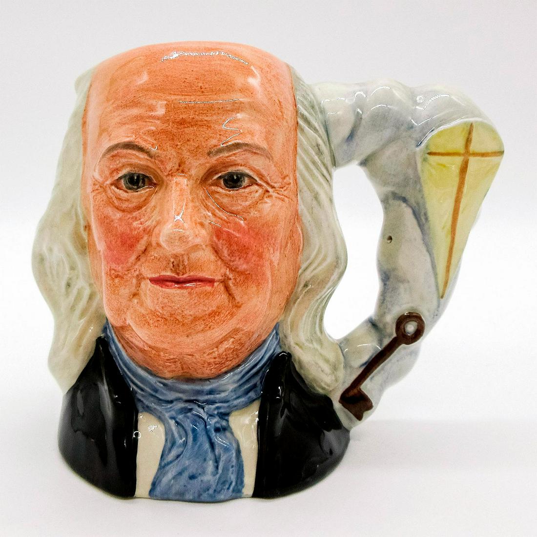 Ben Franklin D6695 - Small - Royal Doulton Character Jug: Black coat; white shirt; blue scarf. Royal Doulton backstamp. Good condition. Artist: Eric Griffiths Issued: 1982 - 1989 Dimensions: 4"H Manufacturer: Royal Doulton Country of Origin: England