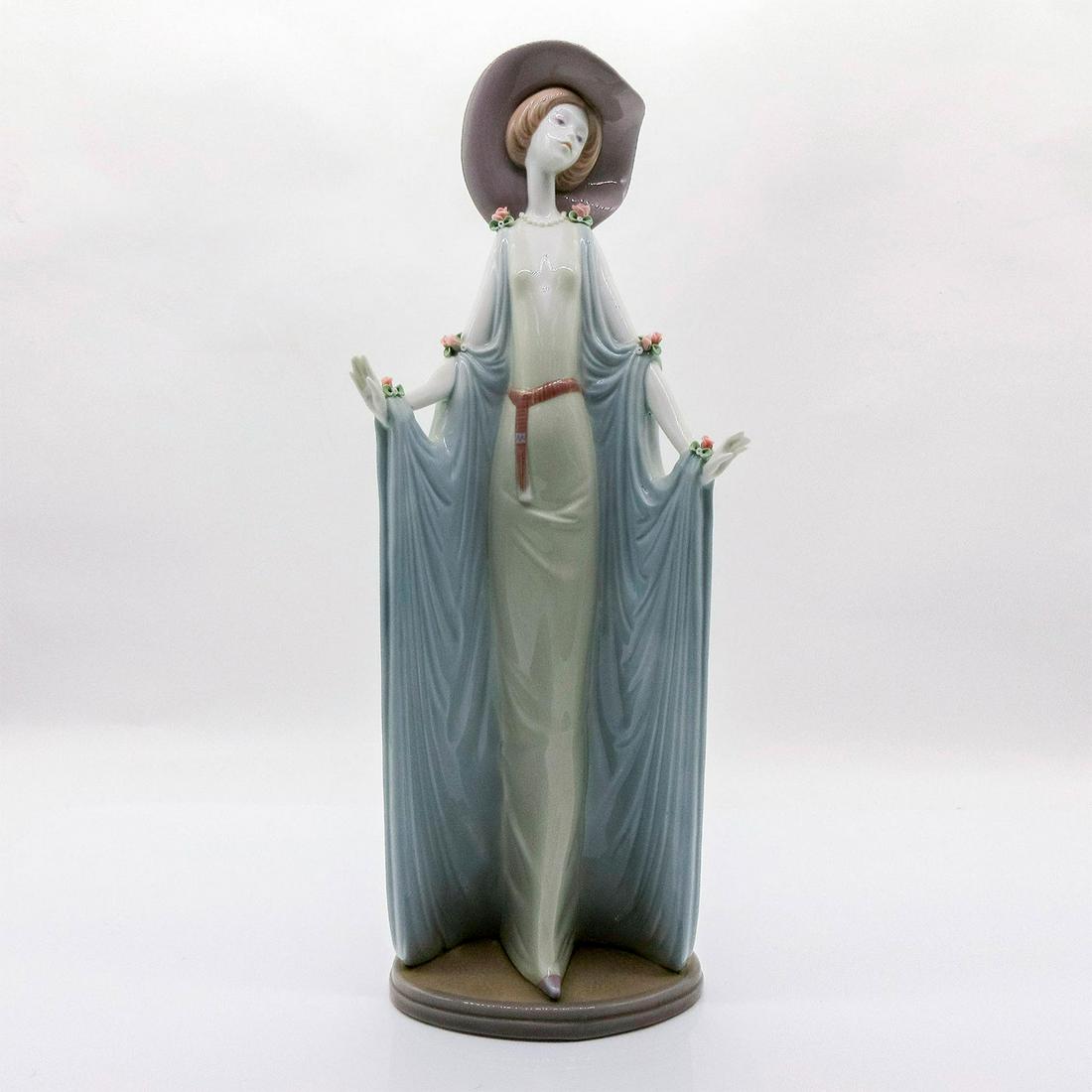 Afternoon Tea 1001428 - Lladro Porcelain Figurine: Glossy finish; Woman in white, blue shawl, pink hat. Lladro backstamp on bottom. Artist: Jose Puche Issued: 1982-1998 Dimensions: 14.25"H x 4.75"W Manufacturer: Lladro Country of Origin: Spain