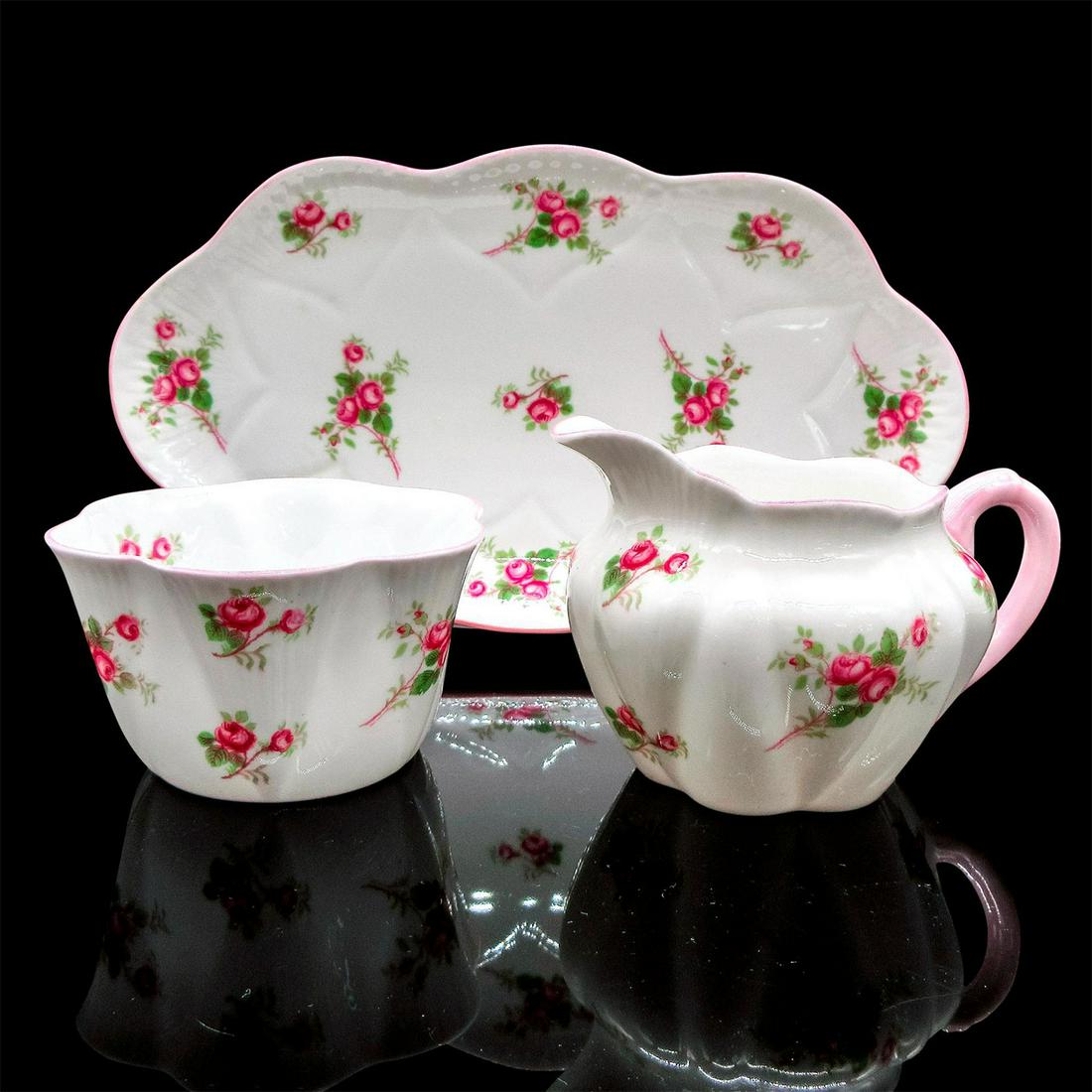 3pc Shelley Creamer, Open Sugar and Tray, Bridal Rose: Vintage bone china tea set; Dainty shape. Scattered pink rose design with pastel pink rim. Shelley England backstamp. 13545 stamped on base. Creamer size - 2.75"H x 4"W. Open sugar size - 2