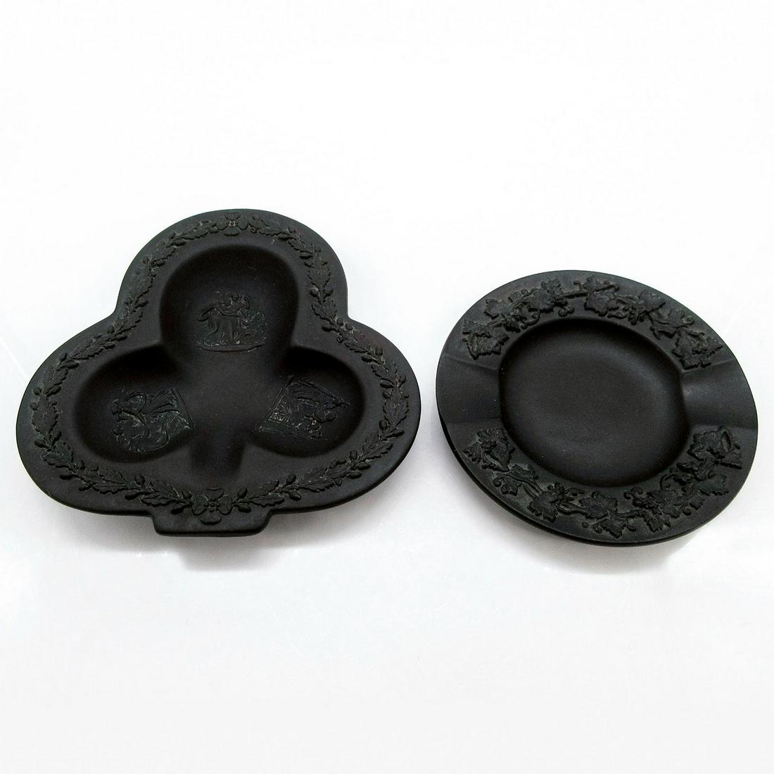 2pc Wedgwood Black Basalt Ashtrays: Small matte ceramic decorative ashtrays; club shaped with Neoclassical reliefs, and circle with arabesque relief. Neoclassical ashtray: 4.5"L x 4.5"W. Arabesque ashtray: 3.5" D. Wedgwood backstamp. #W