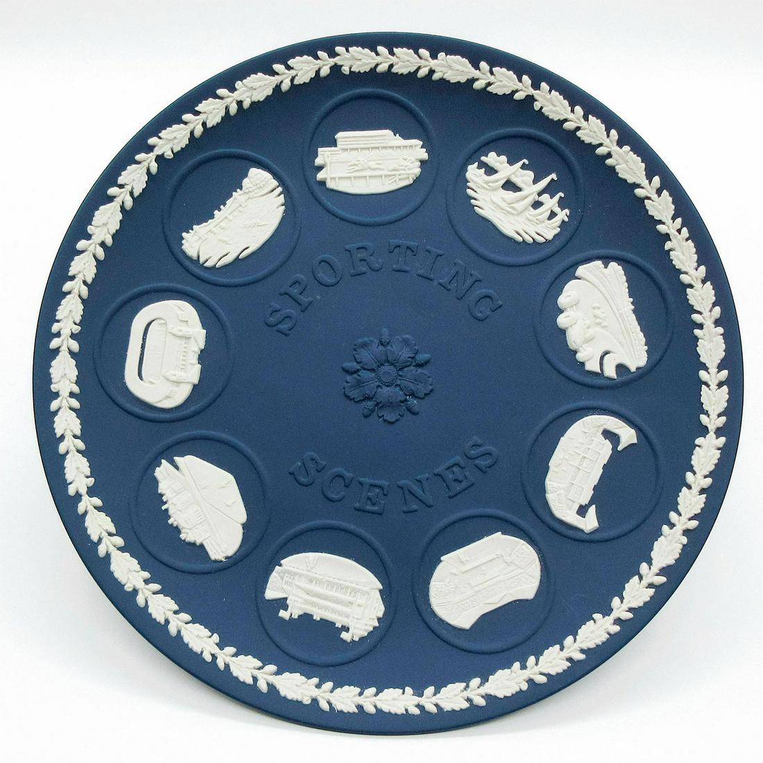 Wedgwood Portland Blue Jasperware, Sporting Scenes Plate: Dark blue jasperware plate featuring nine sporting scenes in sprigged decoration. Wedgwood impressed on the back. Sporting events information are stamped in gold. Weight - 15.3 oz. Minor age related w