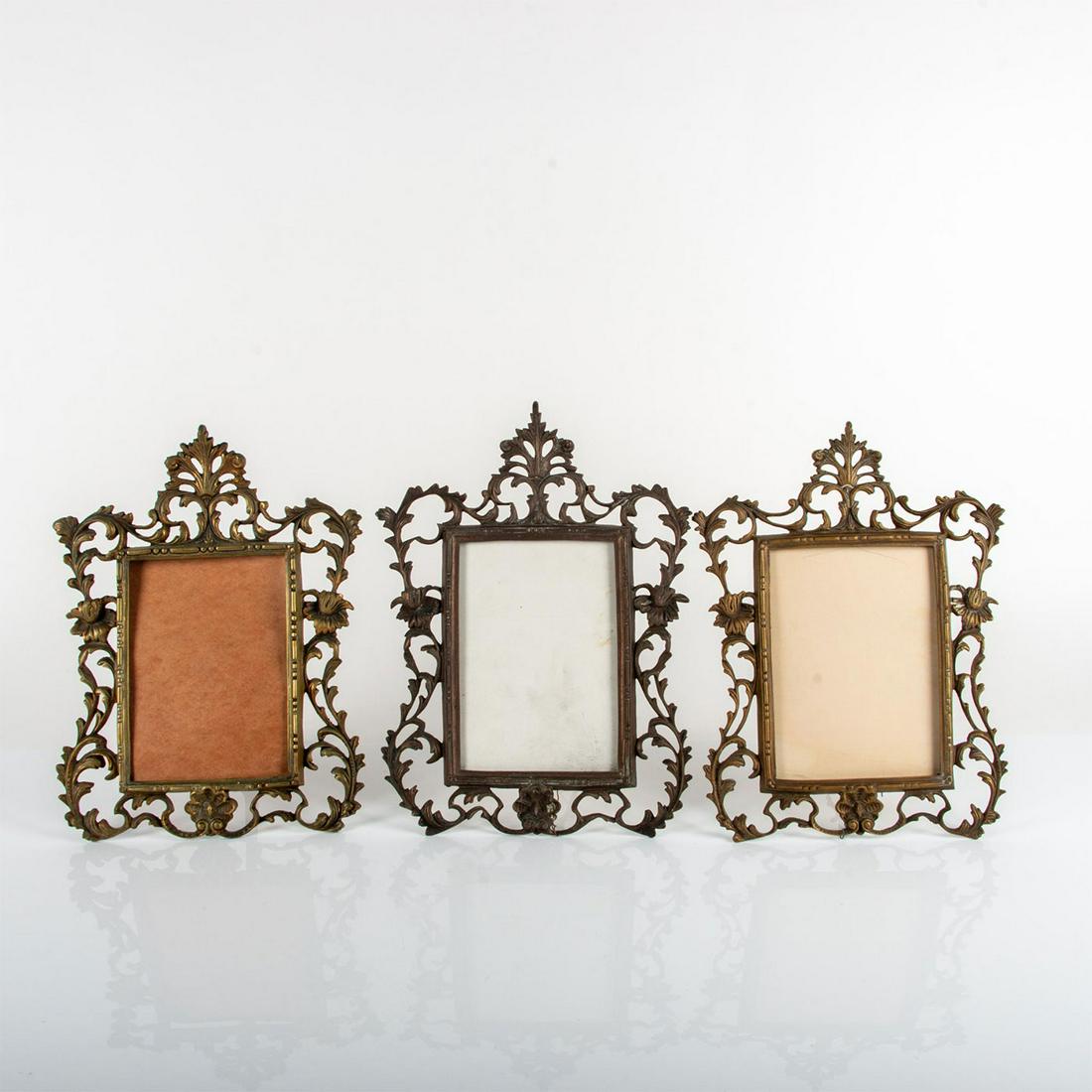 3pc Vintage Cast Metal Tabletop Picture Frames: French style two gold gilded frames and one bronze tone frame; adorned with elegant foliate stalks. Two frames come with glass cover. Gilt frames size - 10.25"W x 14.75"H. Bronze-tone frame size - 11.