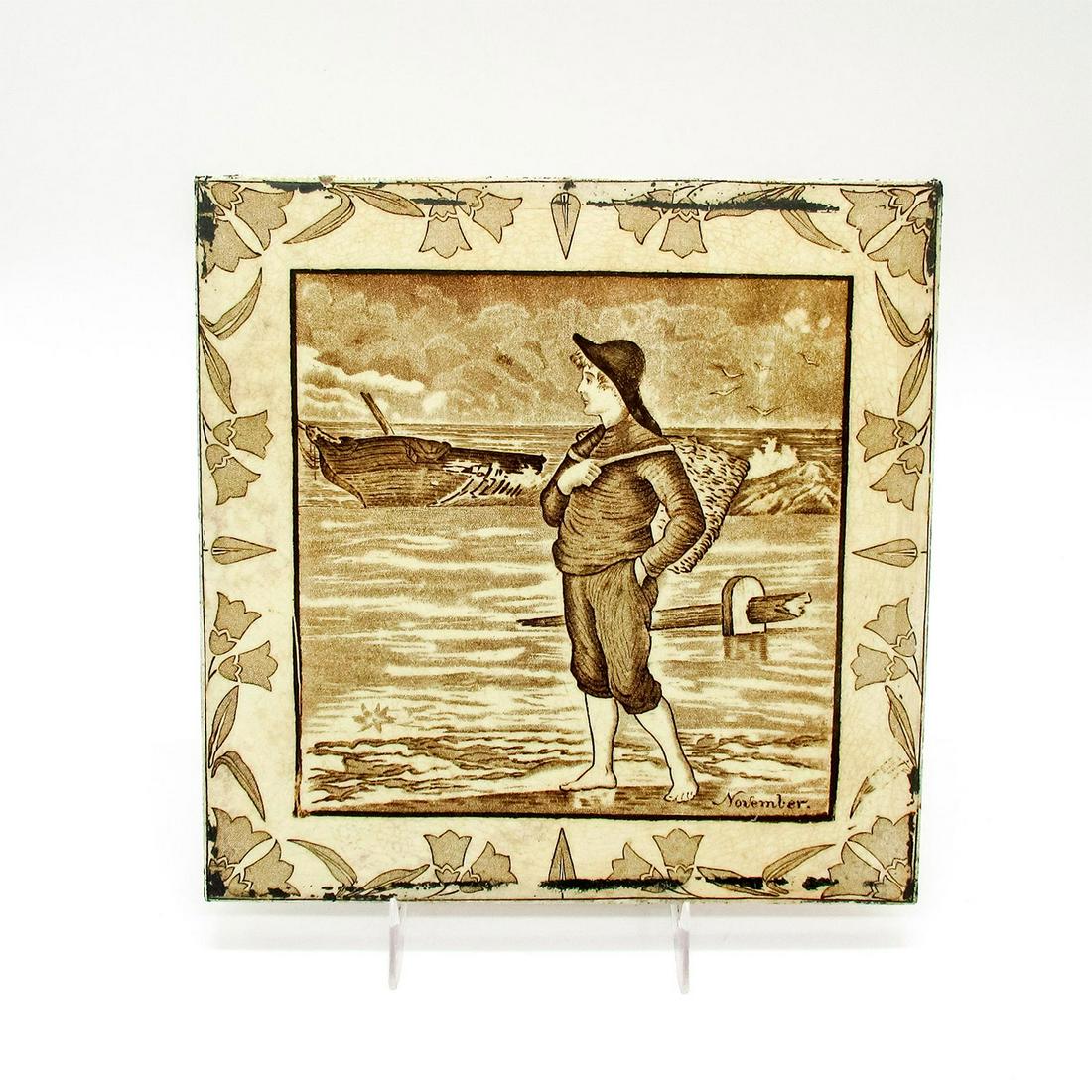 Antique Josiah Wedgwood & Sons Etruria Tile, November: Brown and white transferware image of a young man on the sand at shore's edge with a basket on his back. Josiah Wedgwood & Sons Etruria embossed on the back. Age related crazing seen. Issued: 19th c. 