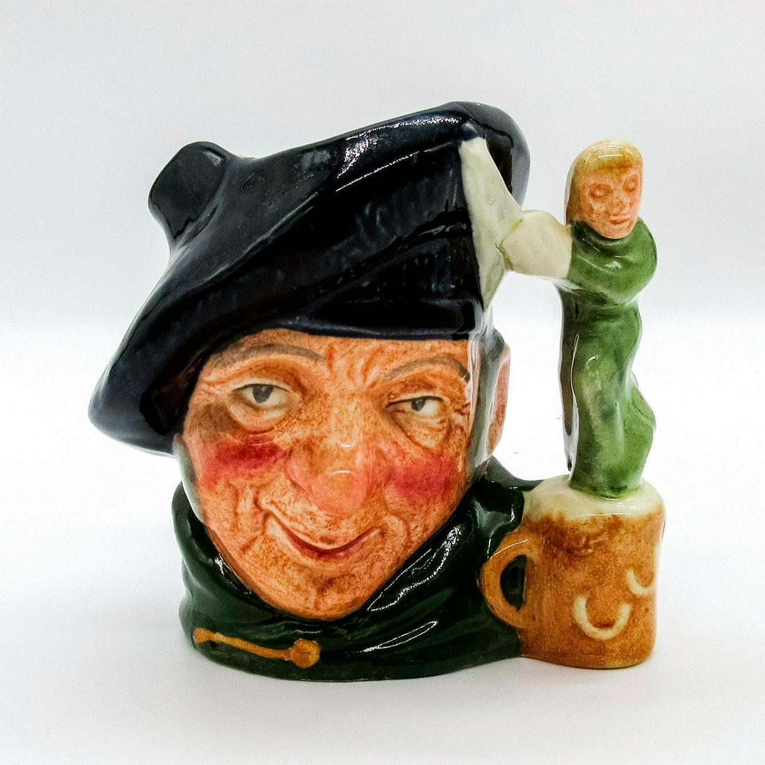 Tam O Shanter D6640 - Mini - Royal Doulton Character Jug: Royal Doulton Character Jug, Tam O'Shanter D6640 (dark blue tam; green cloak). In a poem written by Robert Burns in 1791, Tam O' Shanter is a drunken farmer who happens upon witches who pursue him and