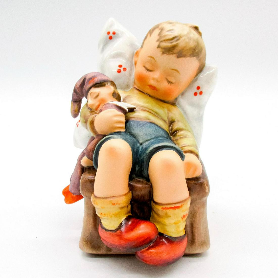Goebel Figurine, Just Dozing 56: An adorable figurine of a boy napping on a chair while holding his jester doll. Includes original box and certificate. Goebel backstamp. Box: 5.25"L x 4"W x 7.5"H. #Goebel Artist: M.J. Hummel Dimensio