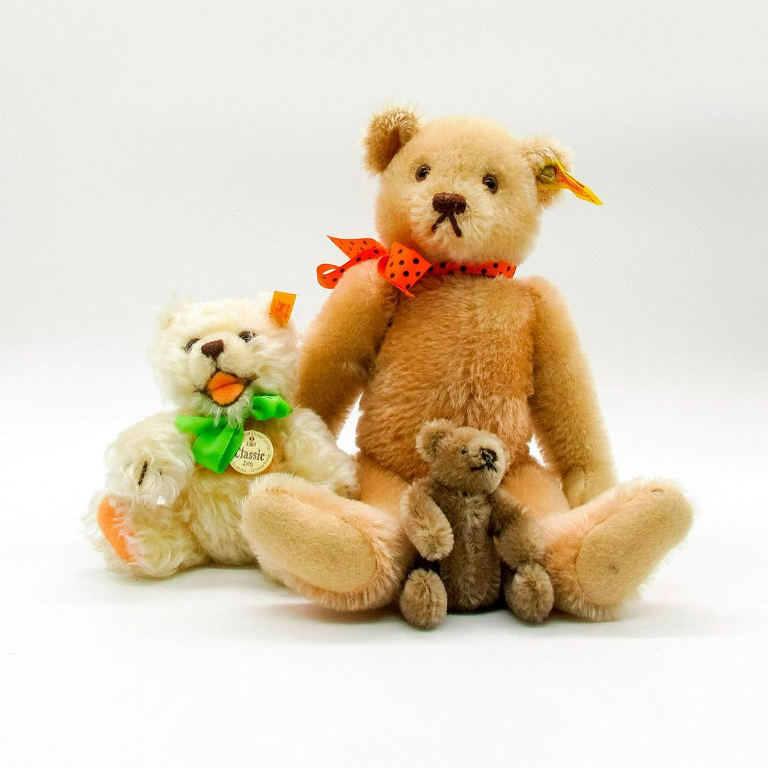 3pc Steiff Stuffed Animals, Teddy Bears: Set of three velveteen and mohair bears of varying brown and blonde shades. Two have articulated arms and legs. Largest has an orange and black polka dot bow, stitched face, and plastic eyes with brow