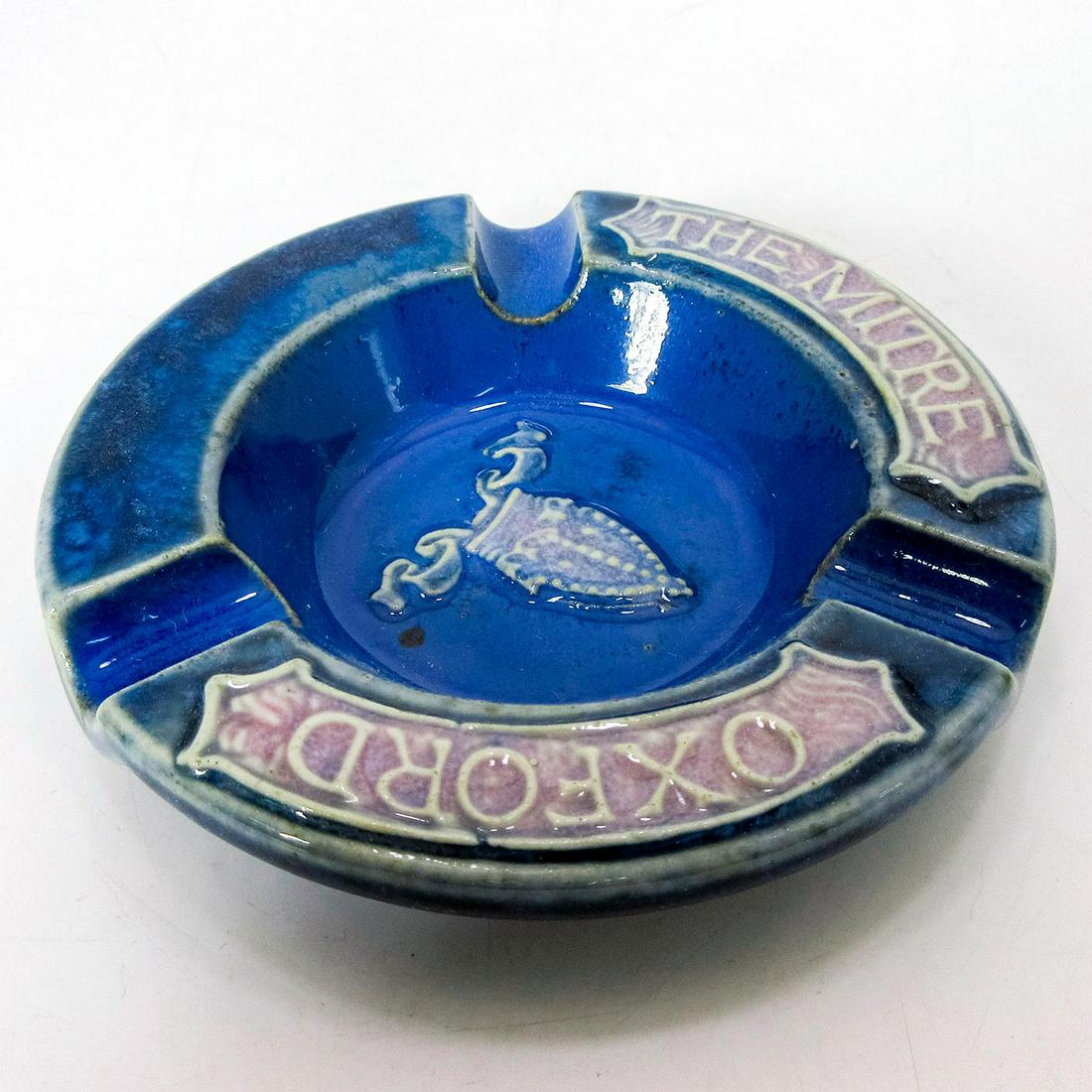 Doulton Lambeth Adware Ashtray The Mitre Oxford: Stoneware in blue coloration, with mitre in center. "The Mitre Oxford" written on front.