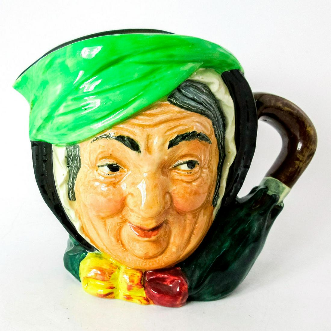 Sairey Gamp D5451 - Large - Royal Doulton Character Jug: Black hair, light green band, dark green coat, yellow and burgundy bow. In Charles Dickens' 1843 novel "Martin Chuzzlewit" Sairey Gamp is a gossiping, gin-drinking midwife and nurse.