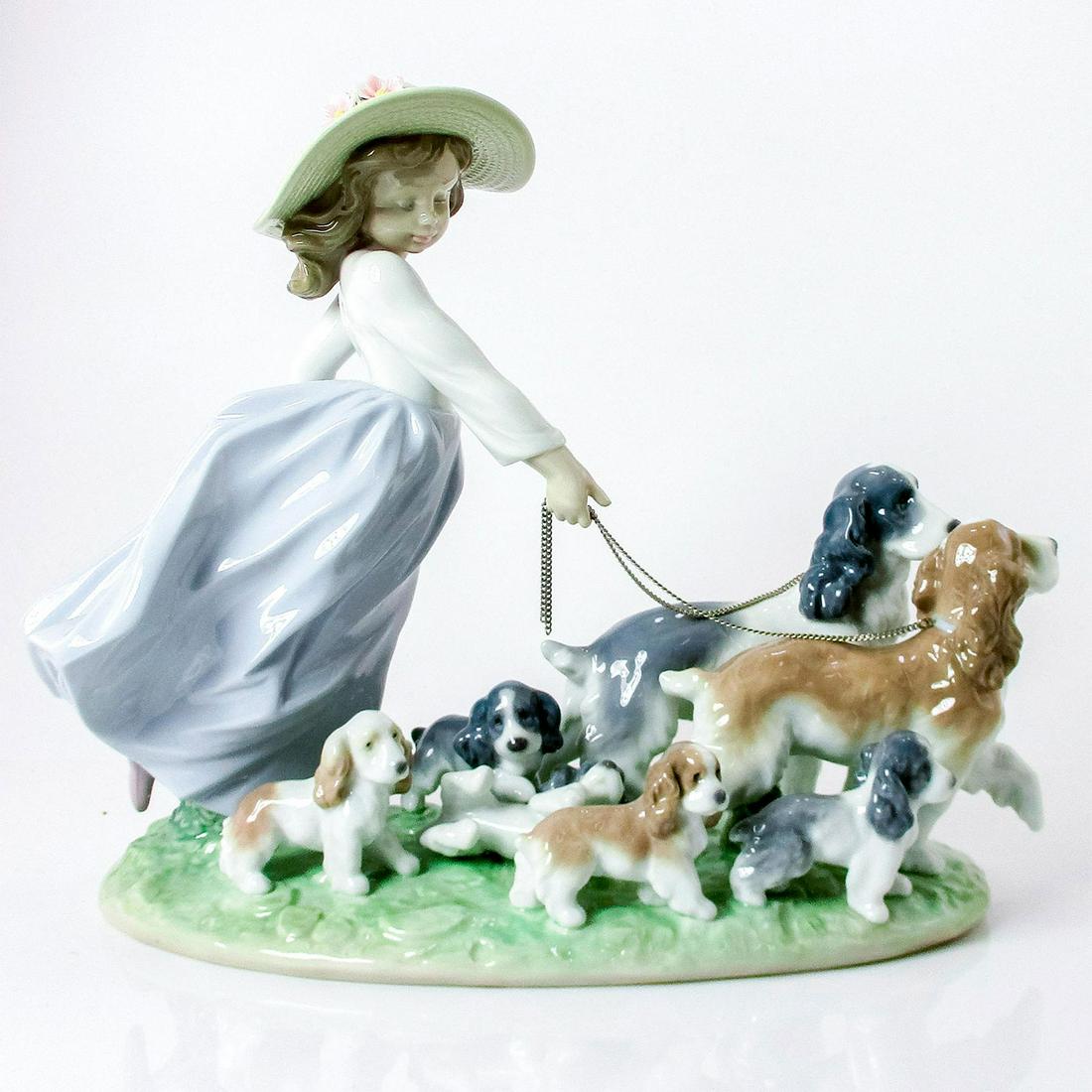Puppy Parade 1006784 - Lladro Porcelain Figurine: Glossy finish; Lladro backstamp. Artist: Antonio Ramos Issued: 2001-2017 Dimensions: 9.5"H x 12.25"W Manufacturer: Lladro Country of Origin: Spain