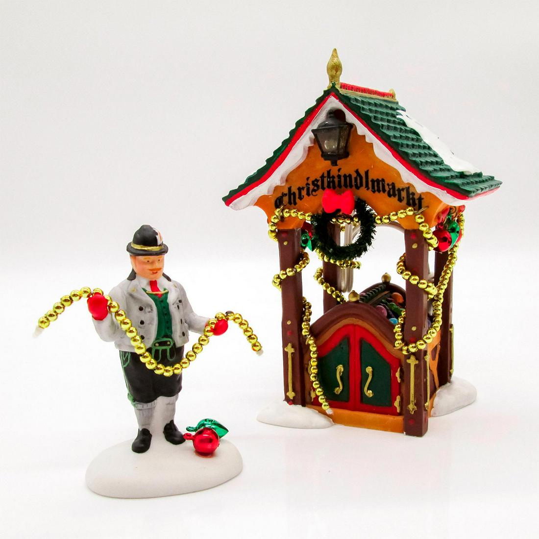 Department 56, Christmas Market, The Ornament Booth: Set of two. First in a set of Christmas ornament figurines. Depicts wooden structure decorated in golden string lights; ornaments inside. Has separate male figure holding golden string of lights. Part