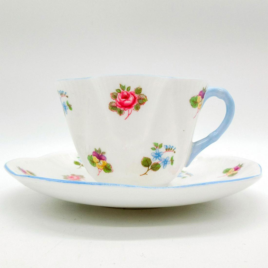 2pc Shelley England Cup and Saucer, Rose Pansy Forget Me Not: Vintage bone china tea set; Dainty shape. Scattered floral design with pale blue rim. Shelley England backstamp. 13424 stamped on base. Cup size - 2.5"H x 3.5" diameter. Saucer size -0.75"H x 5.75" di