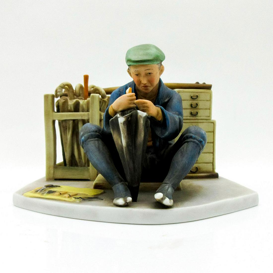 Franklin Porcelain Figurine, Japanese Umbrella Maker: Vibrant fun figural of a street vendor sitting mending an umbrella. Franklin Porcelain backstamp. Umbrella handle is missing. Issued: 1980 Dimensions: 5.25" W x 4" H Manufacturer: Franklin Mint Countr