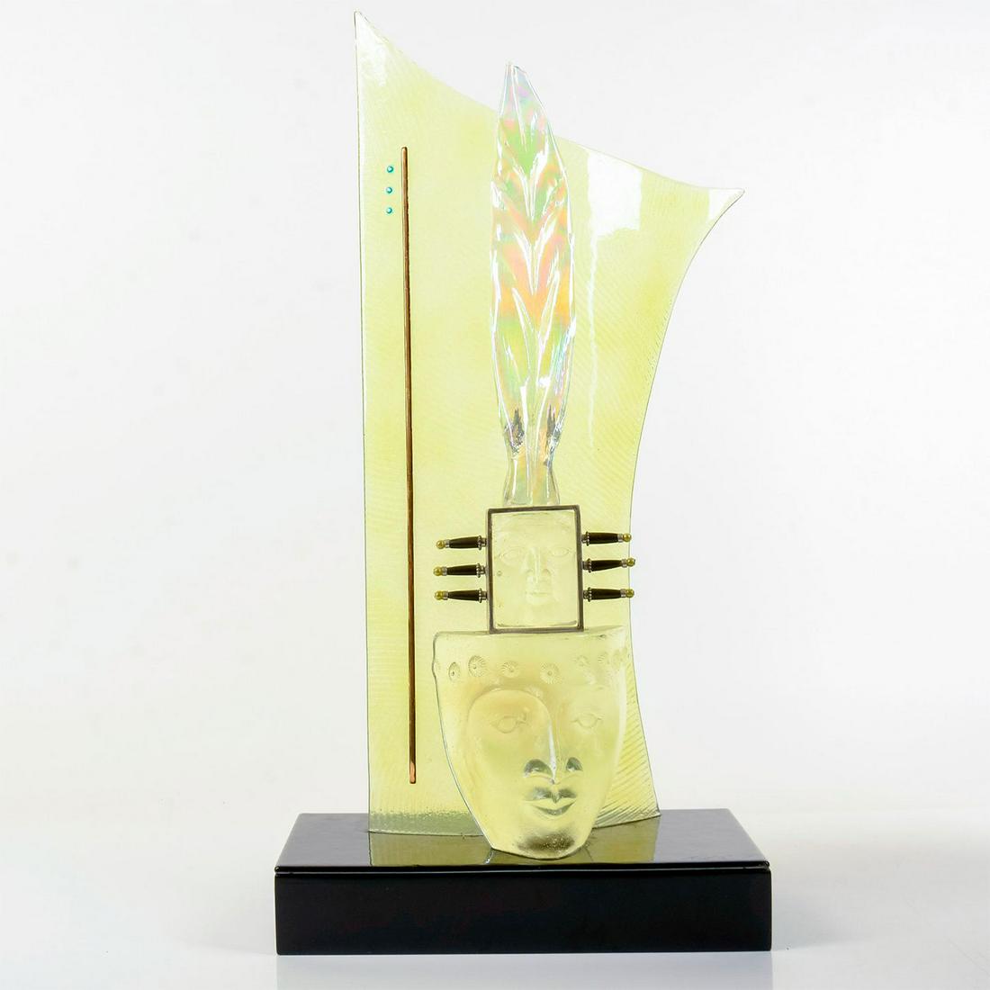 Signed Glass Aztec-Style Sculpture: Two clear idol faces with luminescent feathery headgear placed before a canary-yellow glass backdrop. Artist's signature engraved on the black base. Dimensions: 12" L x 6" W x 24.25" H This item h