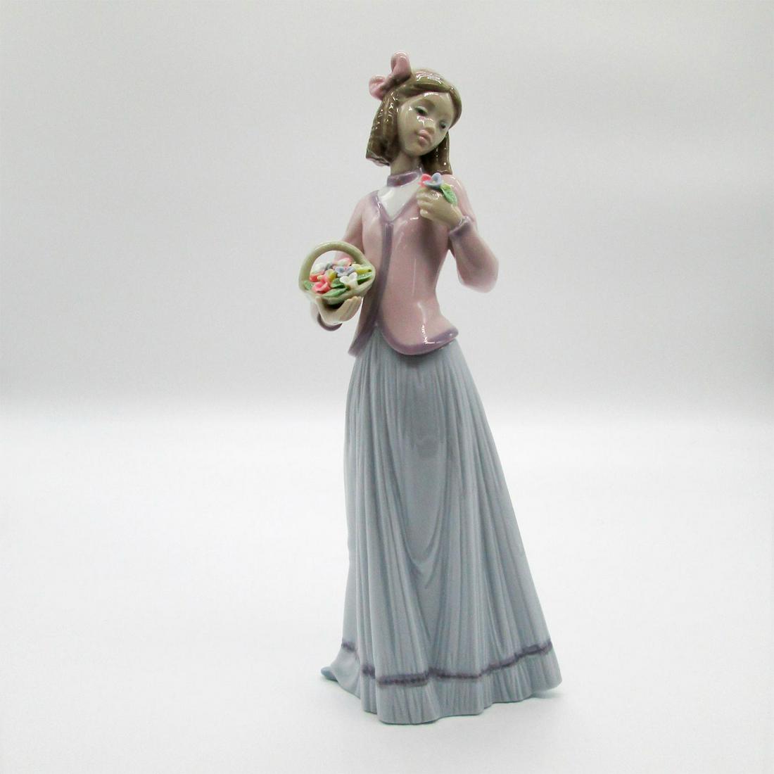 Innocence In Bloom 1007644 - Lladro Porcelain Figurine: Glossy finish; Lladro backstamp. Lladro Collectors Society. Includes original box. Artist: Jose Puche Issued: 1996 Dimensions: 9.75"H x 4.25"W Manufacturer: Lladro Country of Origin: Spain This item h