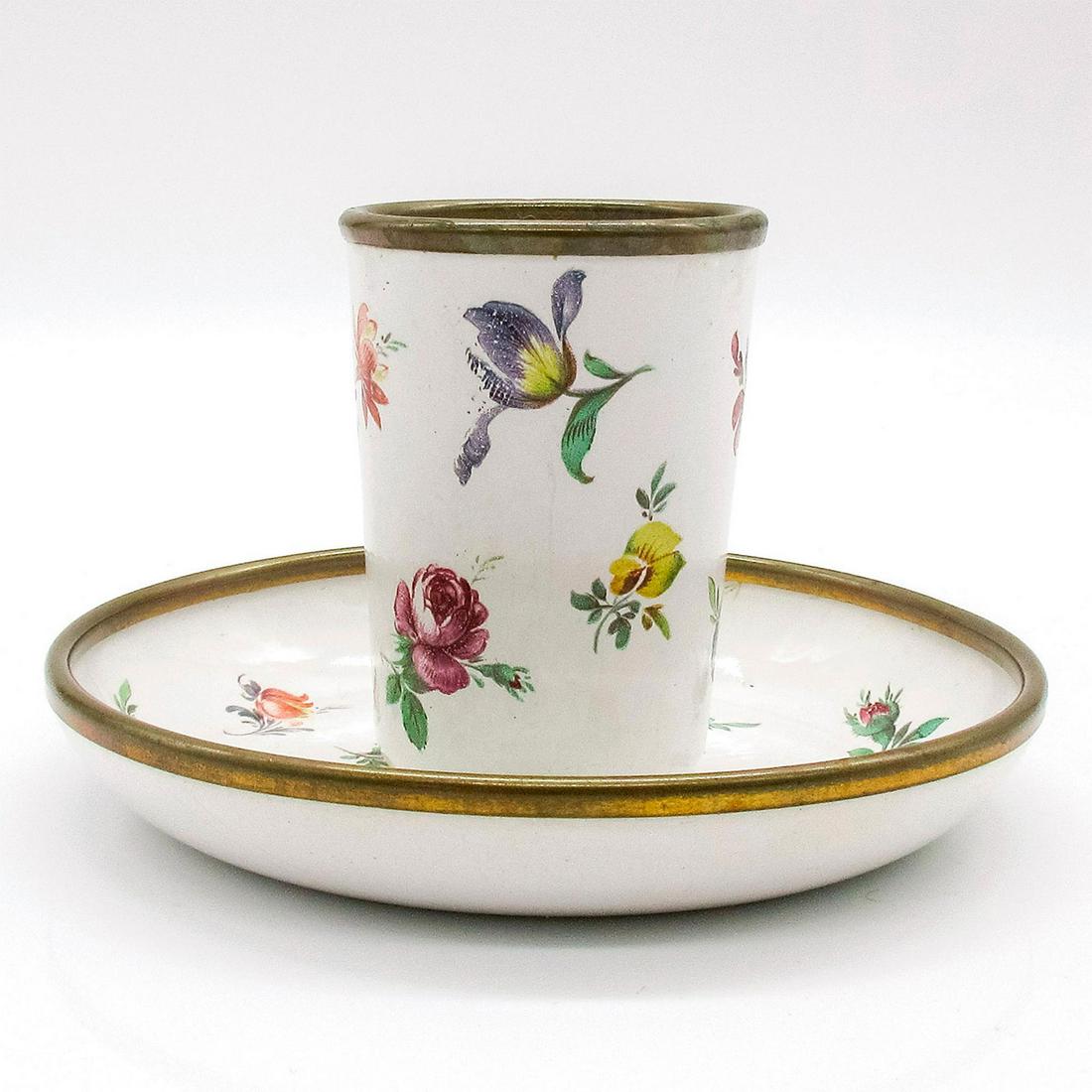 Bilston and Battersea, Tumbler and Saucer: White enamel painted saucer and tumbler set with floral details. Bilston and Battersea stamped to back. Tumbler height 2." Saucer diameter 4". #BilstonandBattersea Issued: 20th c. Manufacturer