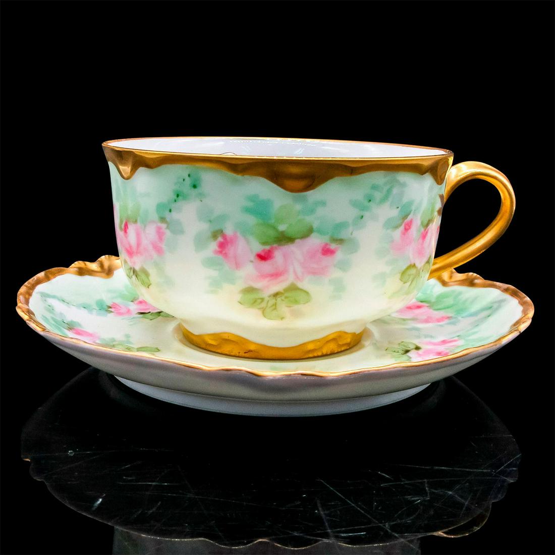 Haviland France Porcelain Mustache Tea Cup and Saucer: White porcelain with hand-painted pink flowers on green leaves design with gold tone rim. Moustache partition to protect moustache from beverage. Haviland France backstamp and decorator signed F. L. B