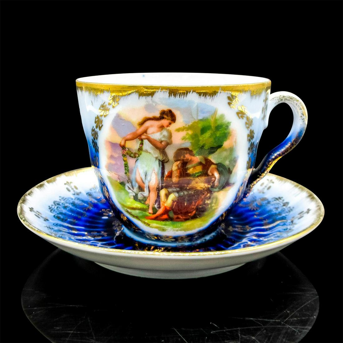Vintage Mustache Tea Cup and Saucer: Elegant set in a deep sapphire blue with a painted scene of two ladies with gold accent design and rim; signed Kauffman. Moustache partition to protect moustache from beverage. Cup size - 3"H x 3.