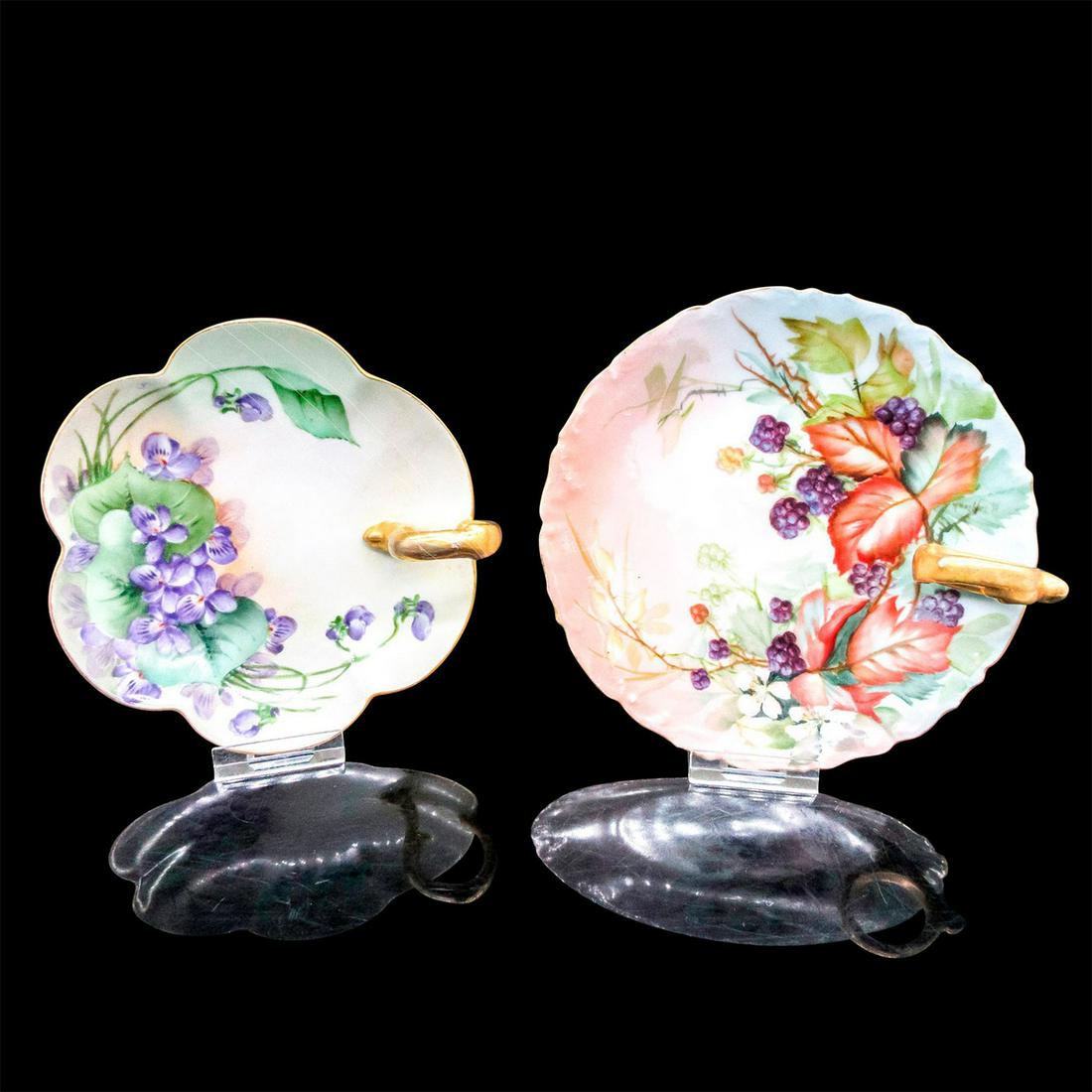 2pc Tressemann & Vogt Nappy Plates: Two painted plates with floral and fruit motifs with gold rim and finger loop. T & V backstamp. The larger - 6" diameter. The smaller - 5.25" diameter. Issued: 20th c. Manufacturer: Tresse