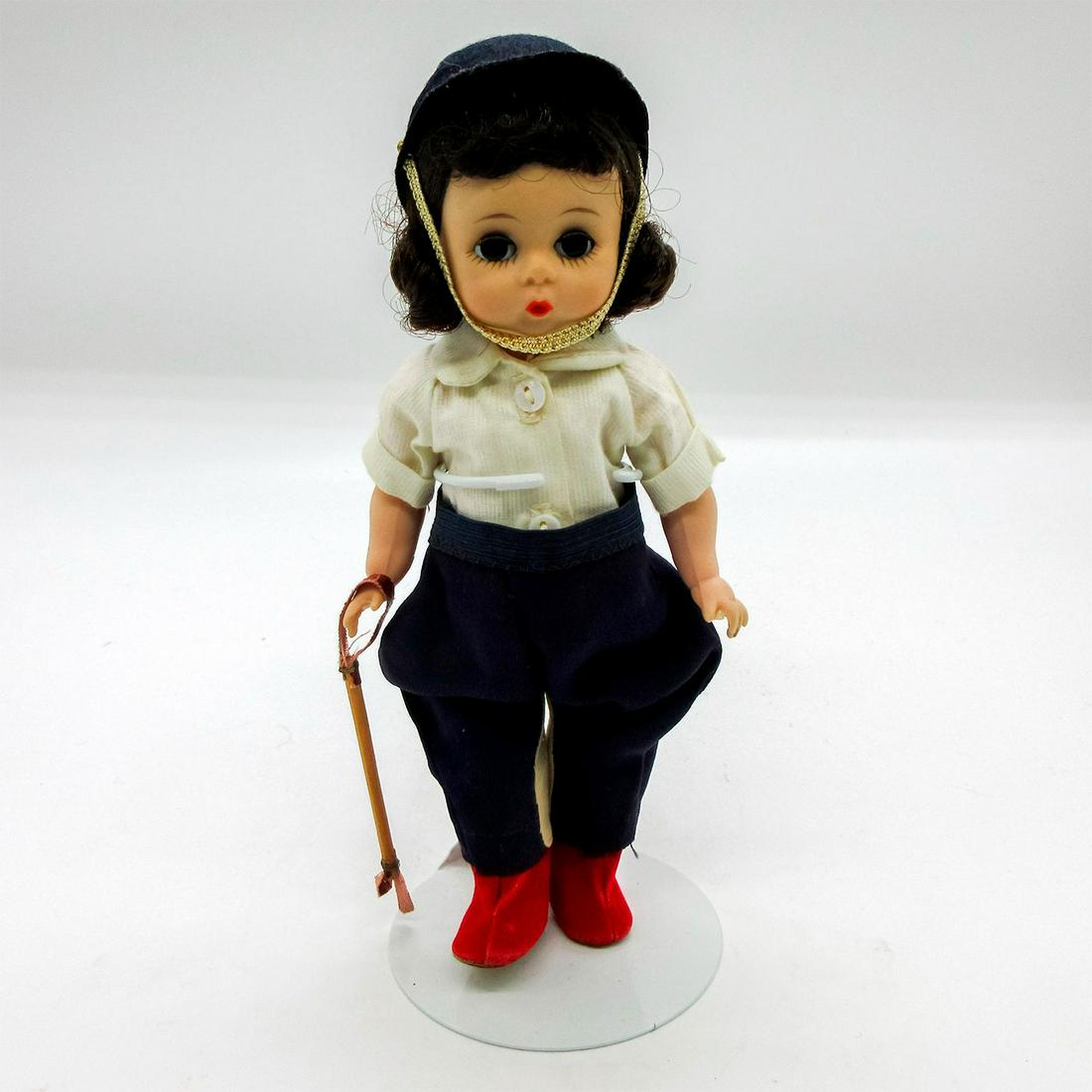 Vintage Madame Alexander Doll, Equestrian: Dressed in blue pants and matching hat, cream shirt, and red shoes. Madame Alexander backstamp on back. Comes with stand. This item has no reserve. Dimensions: 7.5" H Manufacturer: Madame Alexander Co