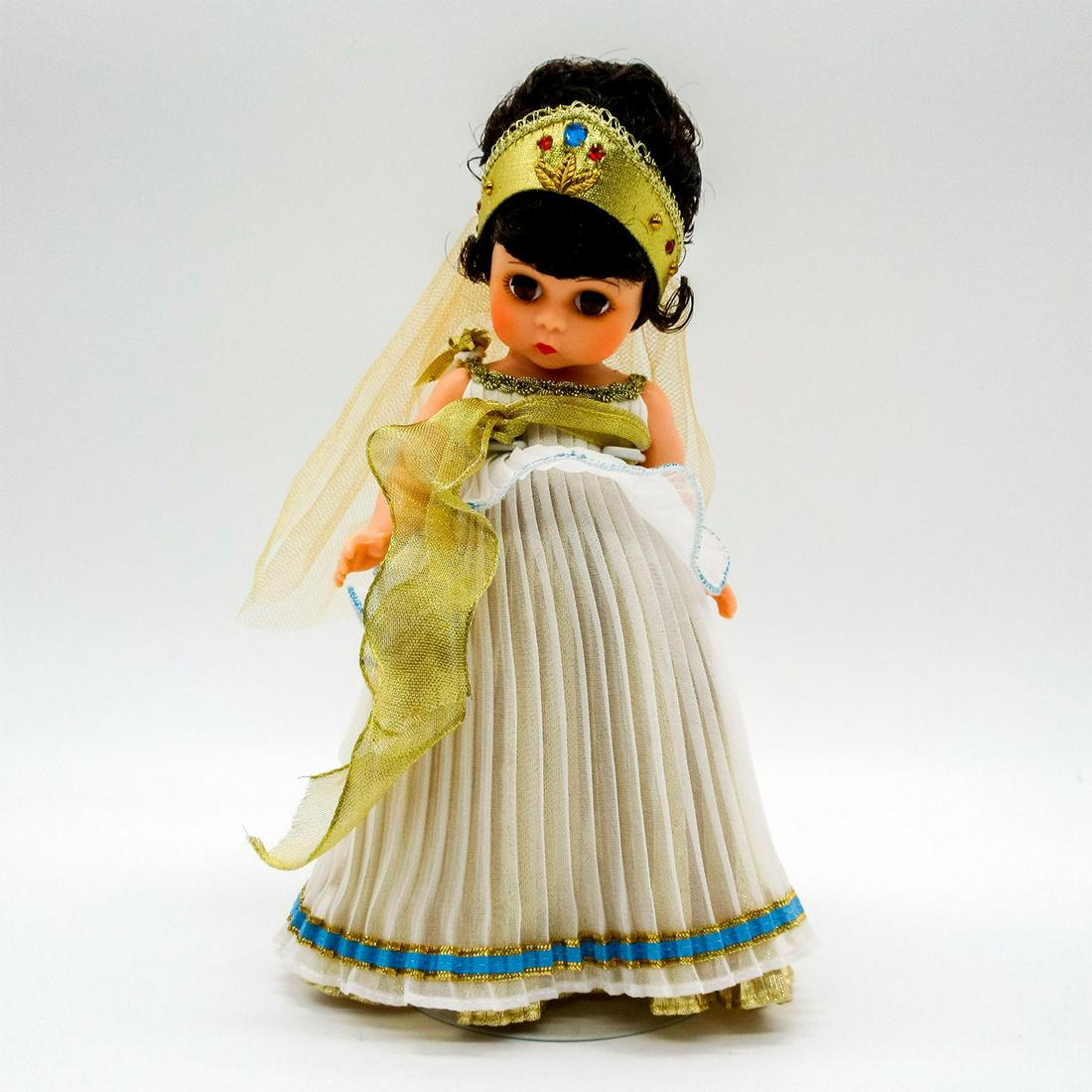 Vintage Madame Alexander Doll, Pandora: Dressed in white and gold pleated dress, with gold tiara and shoes. Madame Alexander backstamp on back. Comes with stand. This item has no reserve. Dimensions: 7.75" H Manufacturer: Madame Alexander C