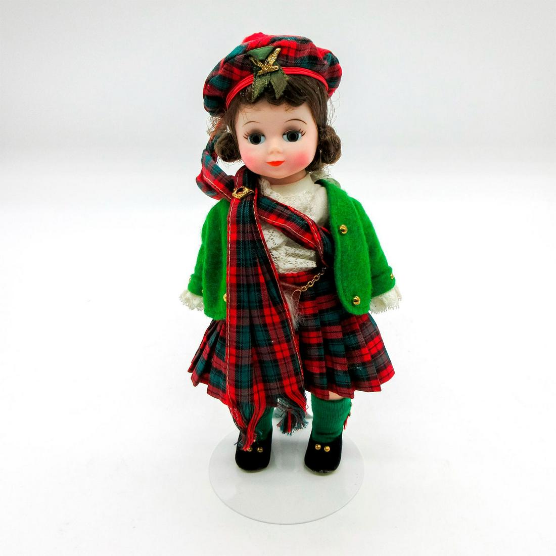 Vintage Madame Alexander Doll, Scottish: Dressed in plaid dress with matching sash and hat, green jacket, and black shoes. Madame Alexander backstamp on back. Comes with stand. This item has no reserve. Dimensions: 7.75" H Manufacturer: Mada