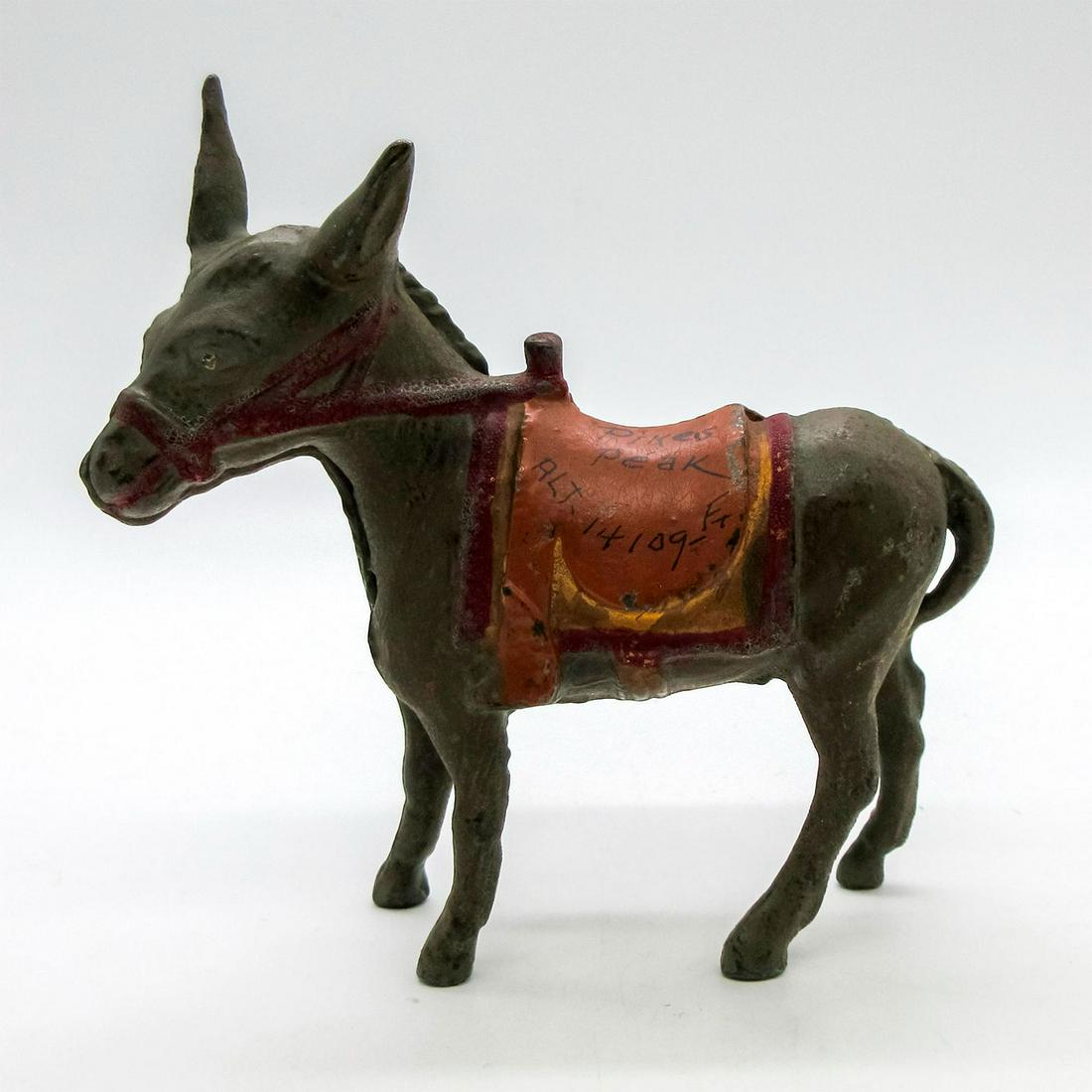 Vintage Pikes Peak Souvenir Donkey Money Bank: Cast iron, depicting donkey with colorful saddle stating "Pikes Peak, Alt. 14109ft." Has coin slot on top of saddle. Pikes Peak was the symbol of the 1859 Gold Rush in Colorado and is the highest summ