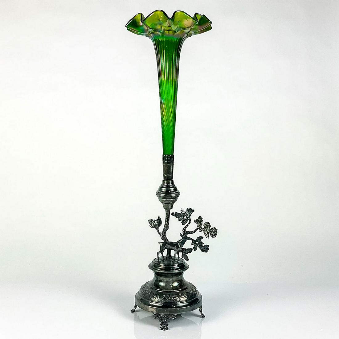 Antique Loetz Glass Art Nouveau Emerald Vase: Emerald-green iridescent trumpet floral shaped vase with silver tone figural ornate base. Unsigned. Dimensions: 6.25" L x 5.5" W x 20" H Manufacturer: Loetz Country of Origin: Austria